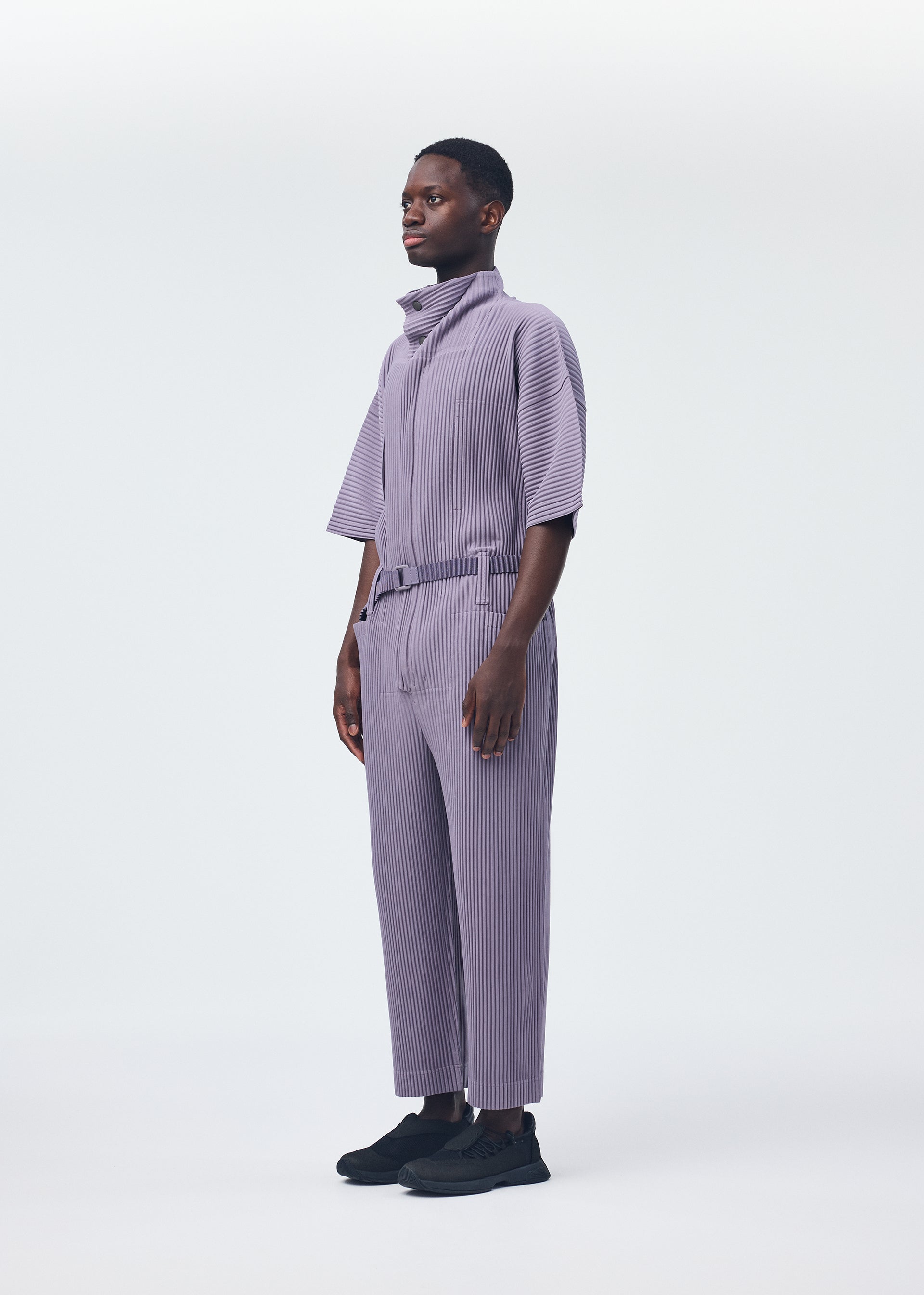 A model wears the HOMME PLISSÉ ISSEY MIYAKE PLEATS BOTTOMS 1 jumpsuit.