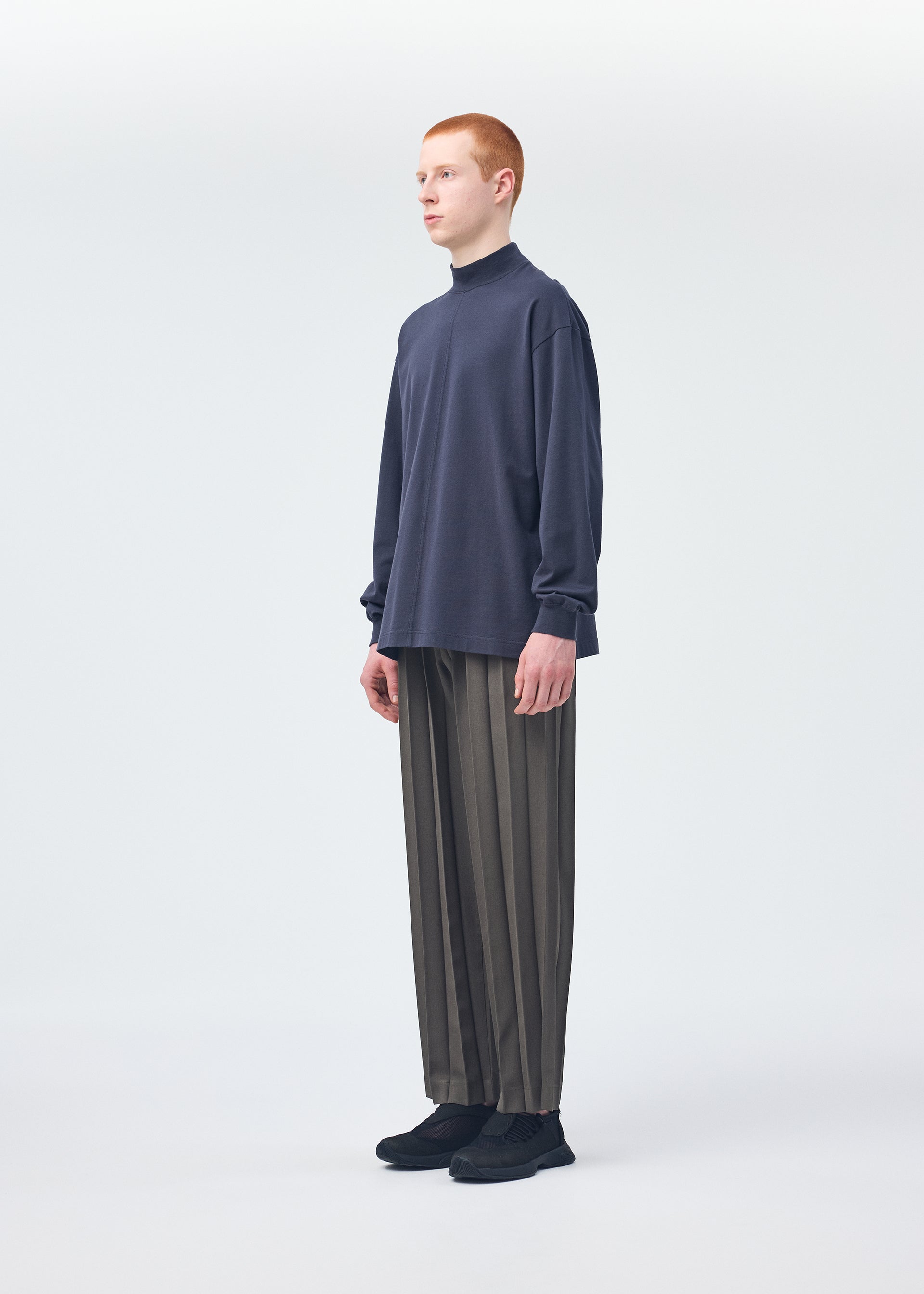 A model wears the HOMME PLISSÉ ISSEY MIYAKE Black Turtleneck Top top.