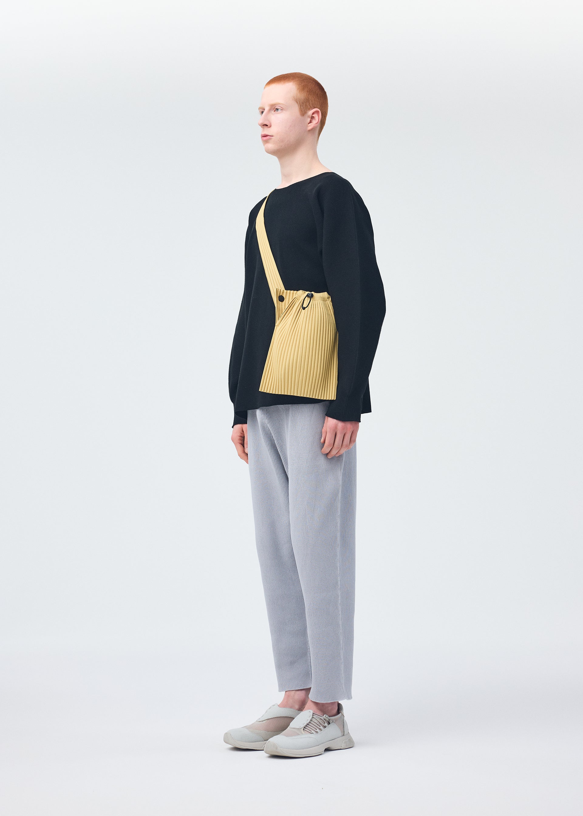 A model wears the HOMME PLISSÉ ISSEY MIYAKE BASIC KNIT top.