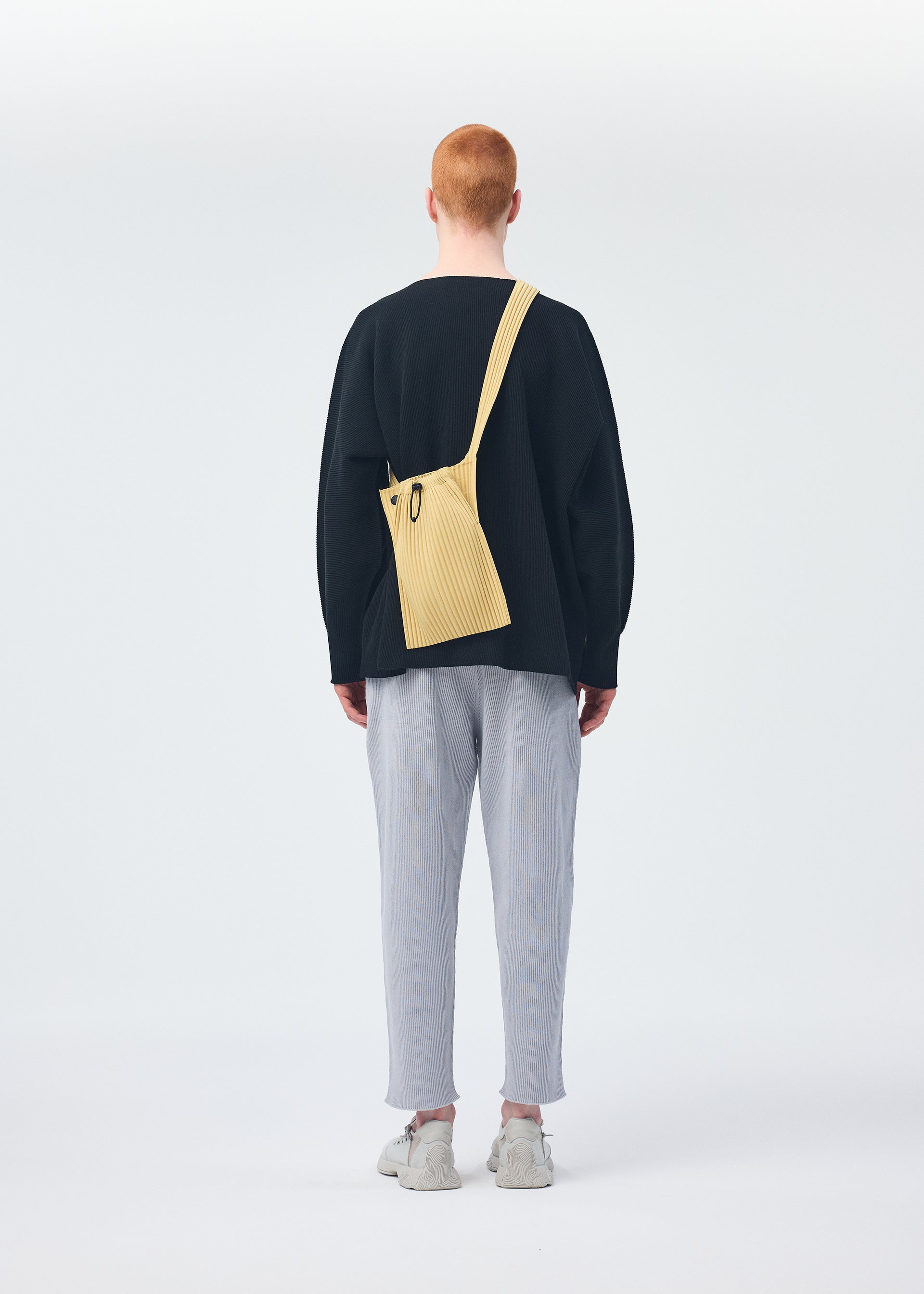 A model wears the HOMME PLISSÉ ISSEY MIYAKE BASIC KNIT top.