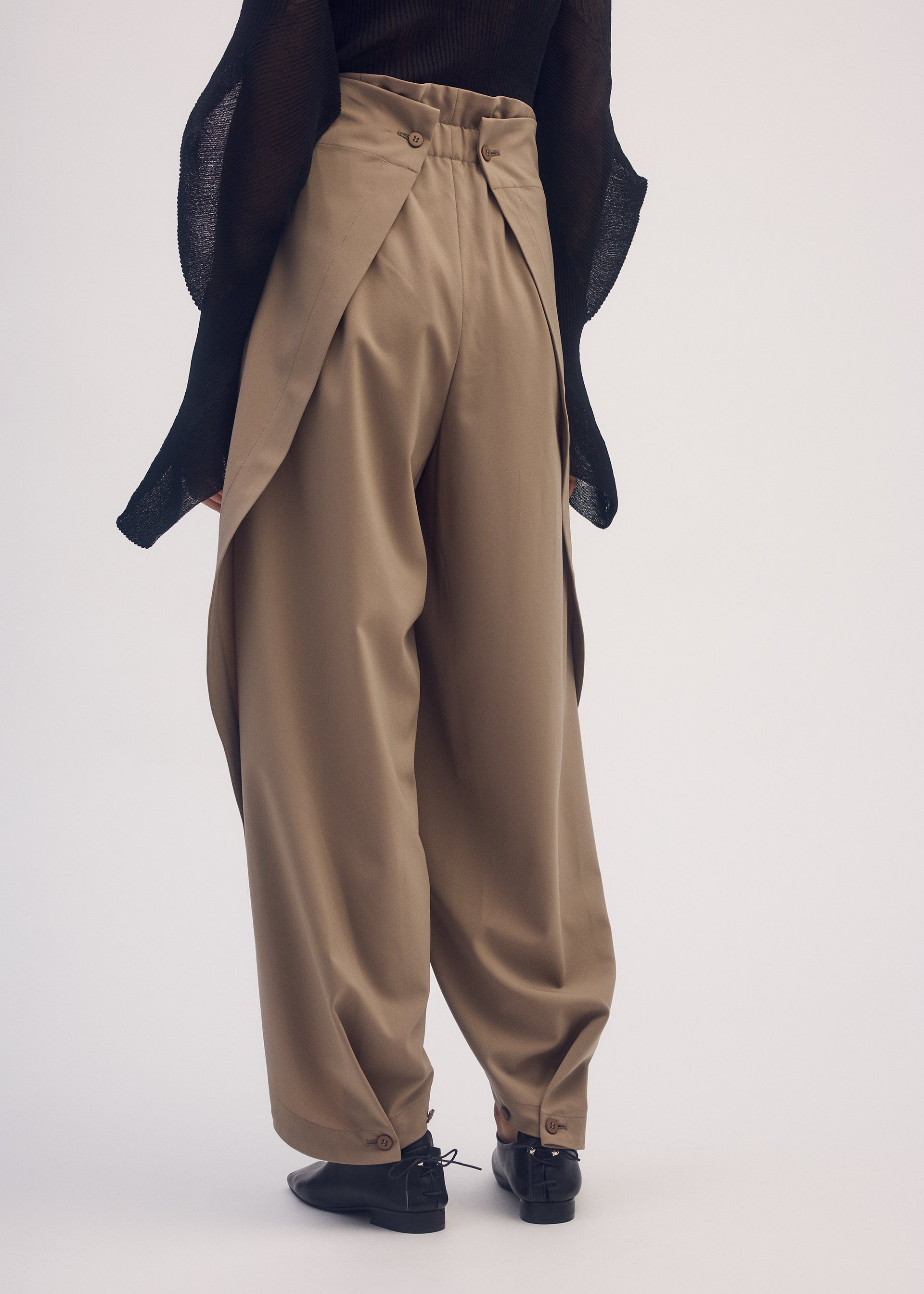 A model wears the ISSEY MIYAKE ROUND PANTS trousers.