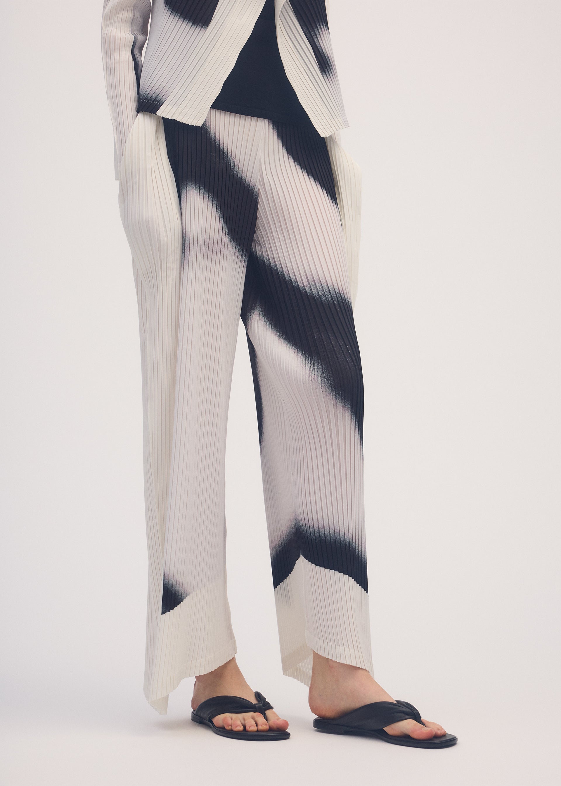 A model wears the ISSEY MIYAKE SHADOW STUDY PLEATS trousers.