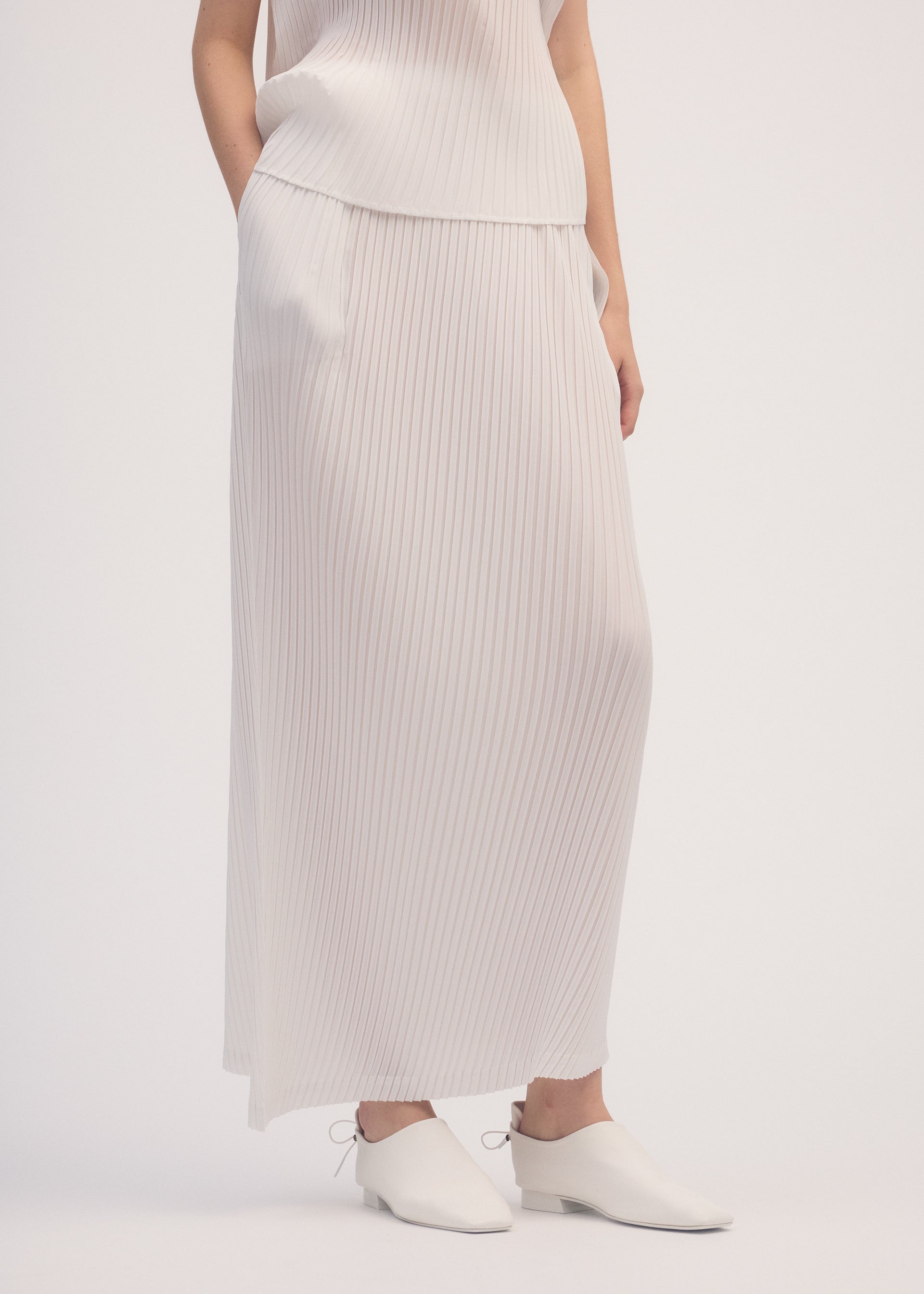 A model wears the ISSEY MIYAKE SHADOW STUDY PLEATS SOLID skirt.
