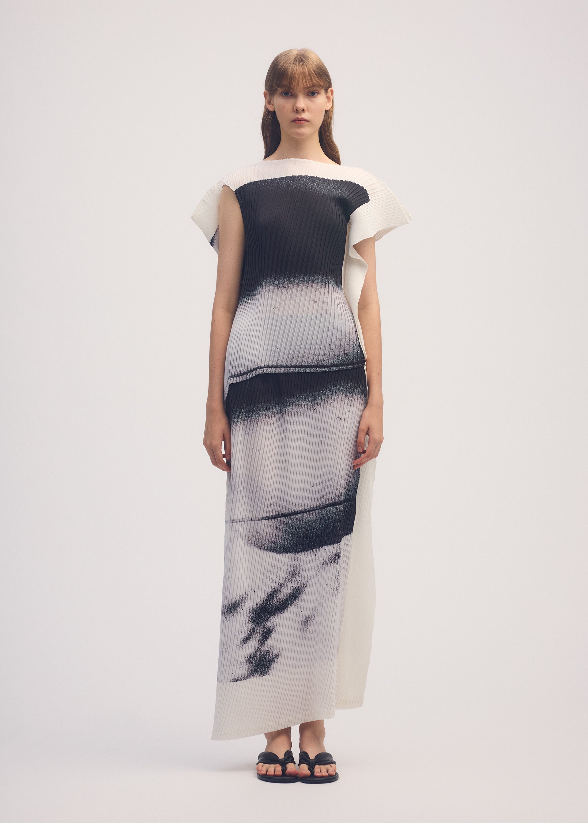A model wears the ISSEY MIYAKE SHADOW STUDY PLEATS skirt.
