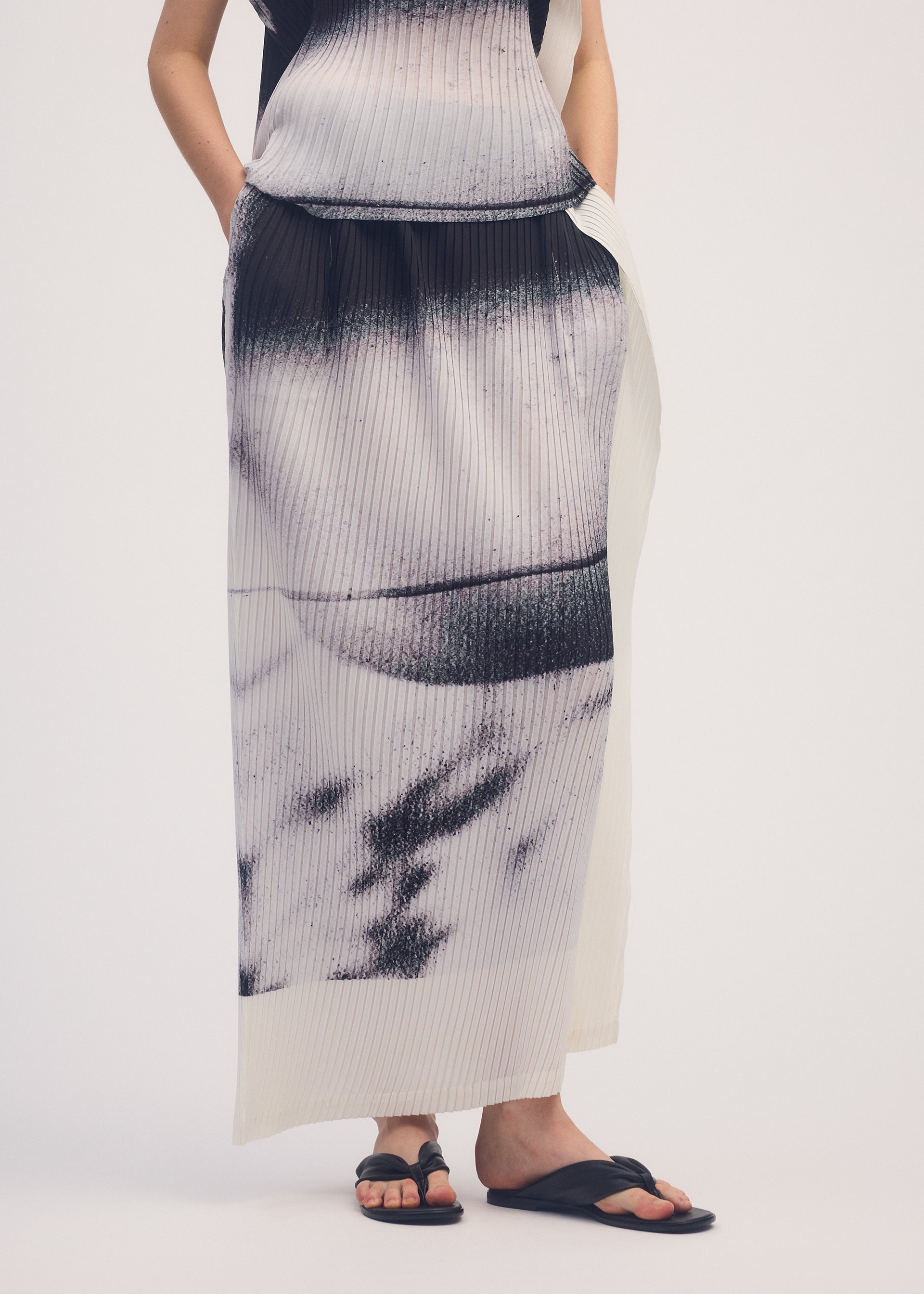 A model wears the ISSEY MIYAKE SHADOW STUDY PLEATS skirt.