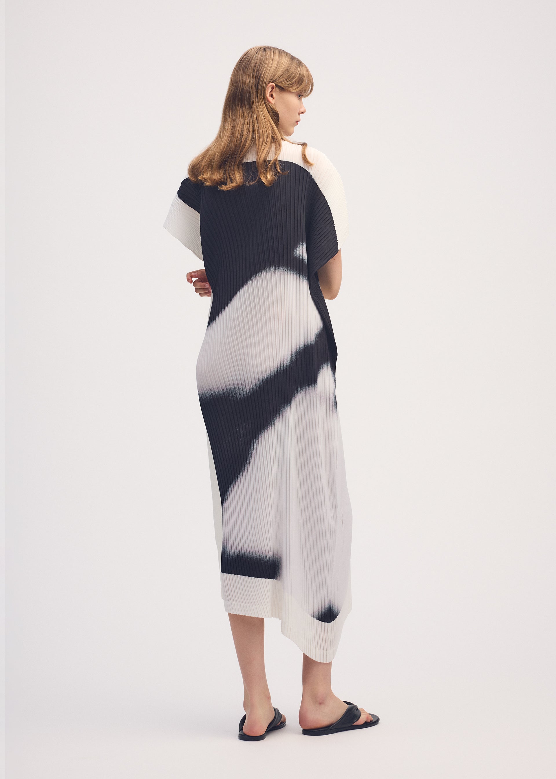 A model wears the ISSEY MIYAKE SHADOW STUDY PLEATS dress.