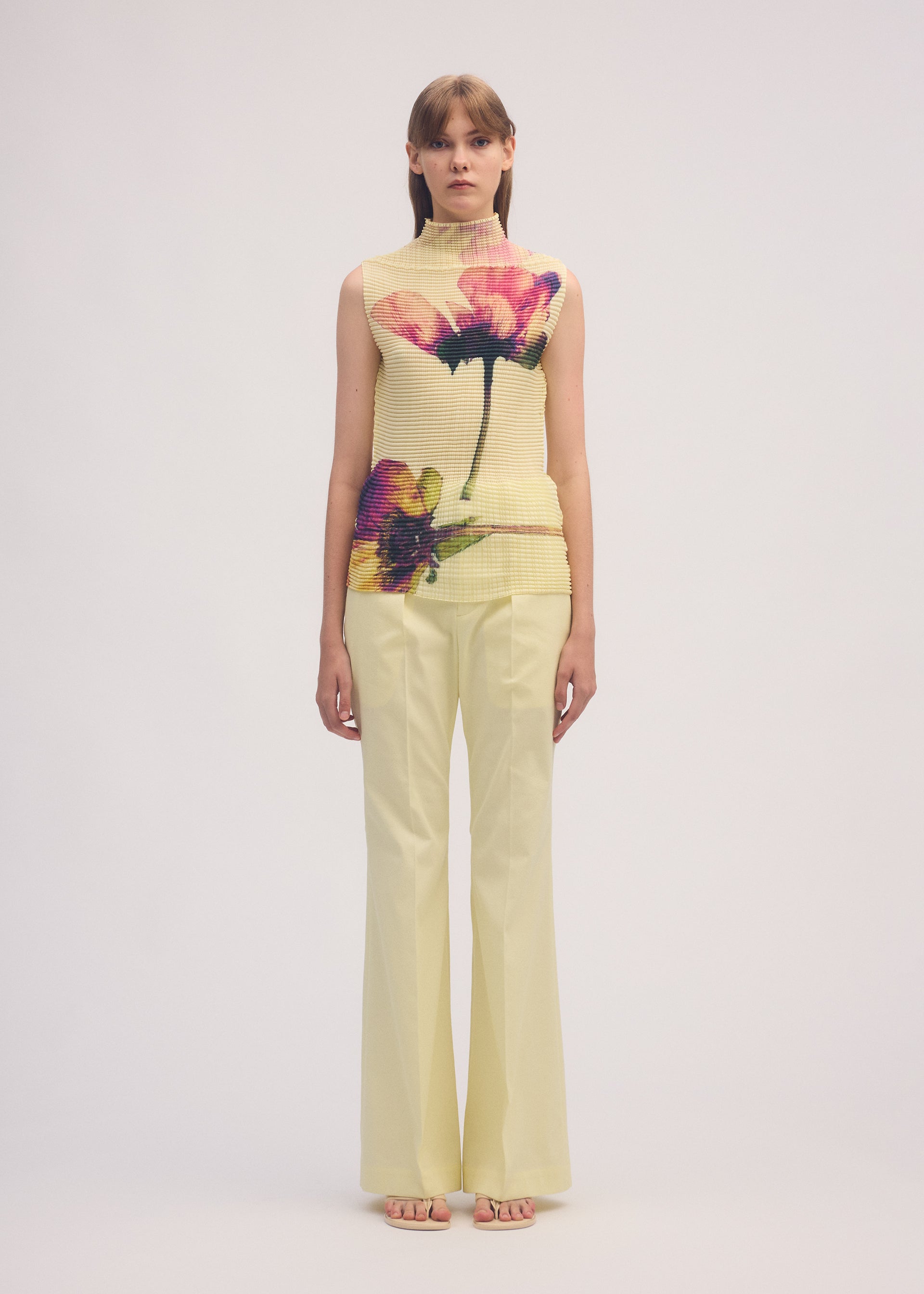 A model wears the ISSEY MIYAKE PRESSED FLORA PLEATS TOP shirt.