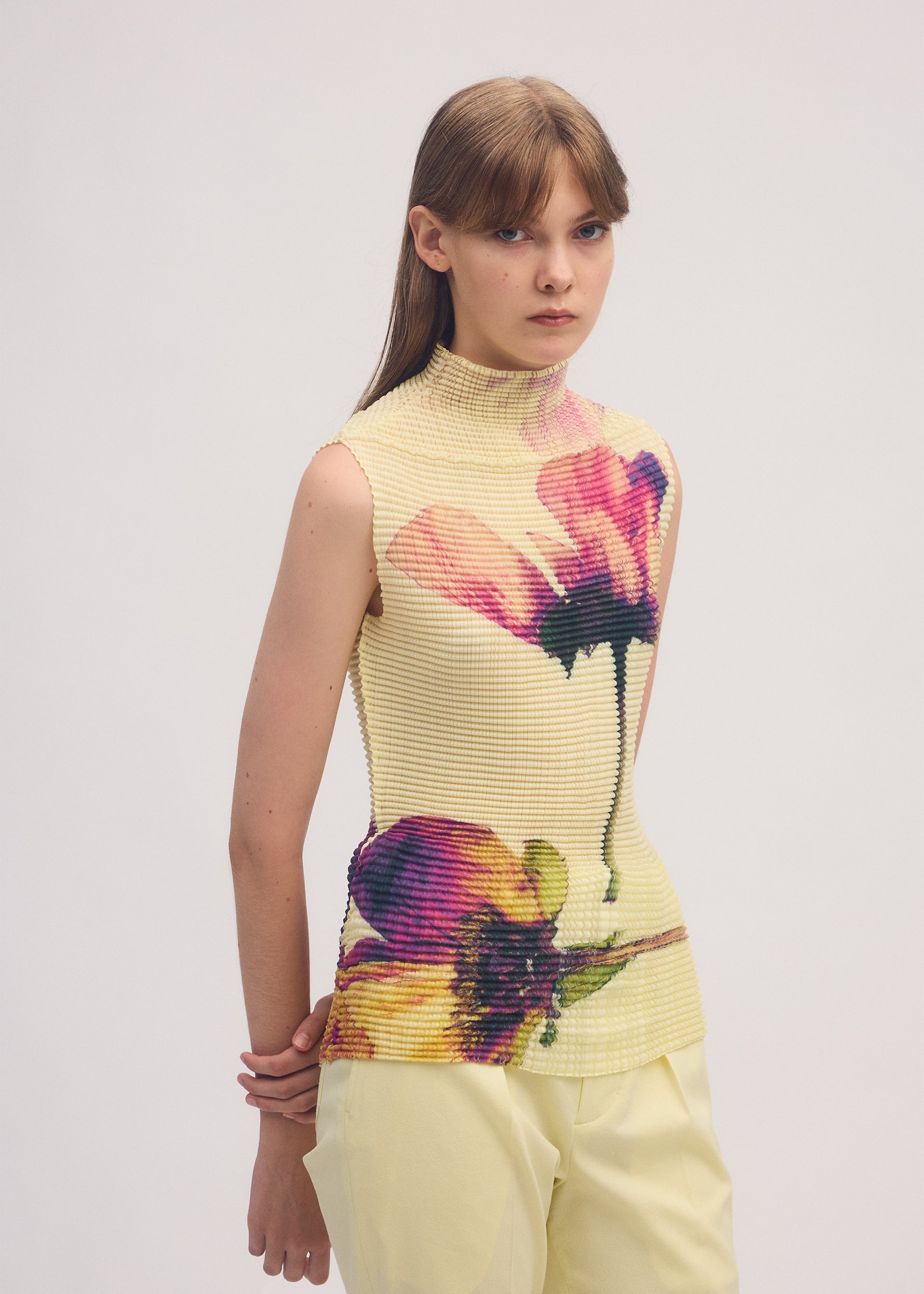 A model wears the ISSEY MIYAKE PRESSED FLORA PLEATS TOP shirt.