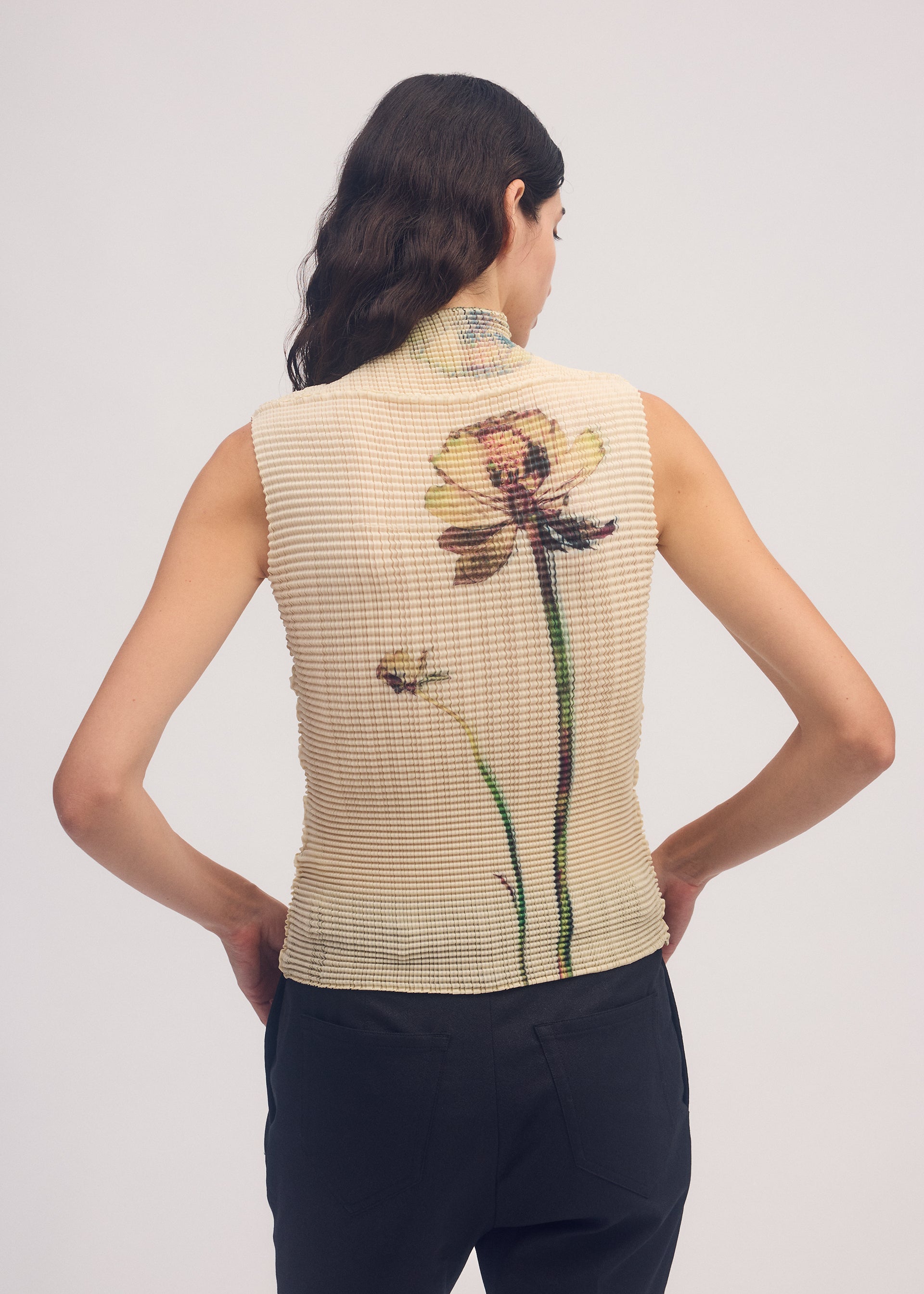 A model wears the ISSEY MIYAKE PRESSED FLORA PLEATS TOP shirt.