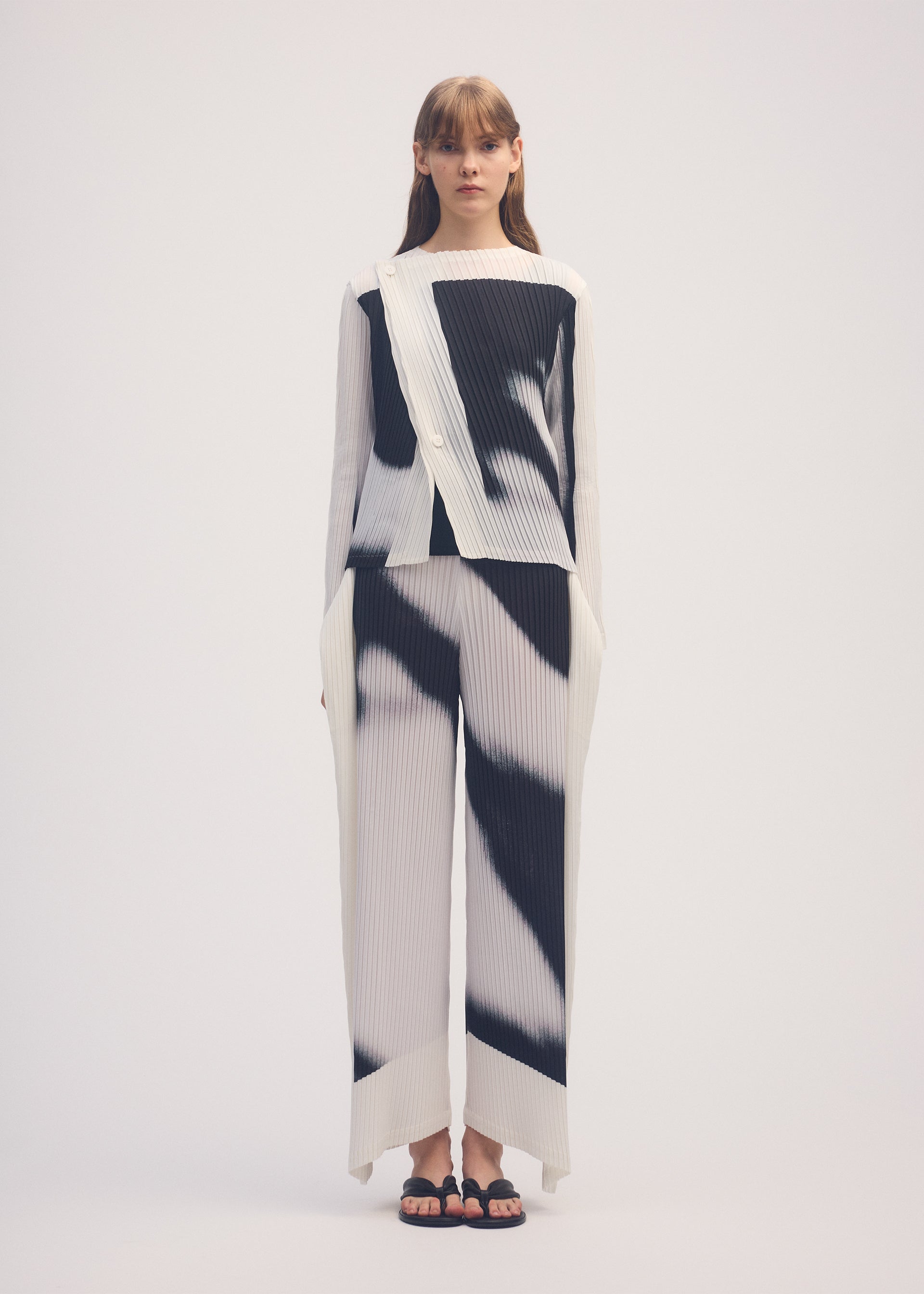 A model wears the ISSEY MIYAKE SHADOW STUDY PLEATS cardigan.