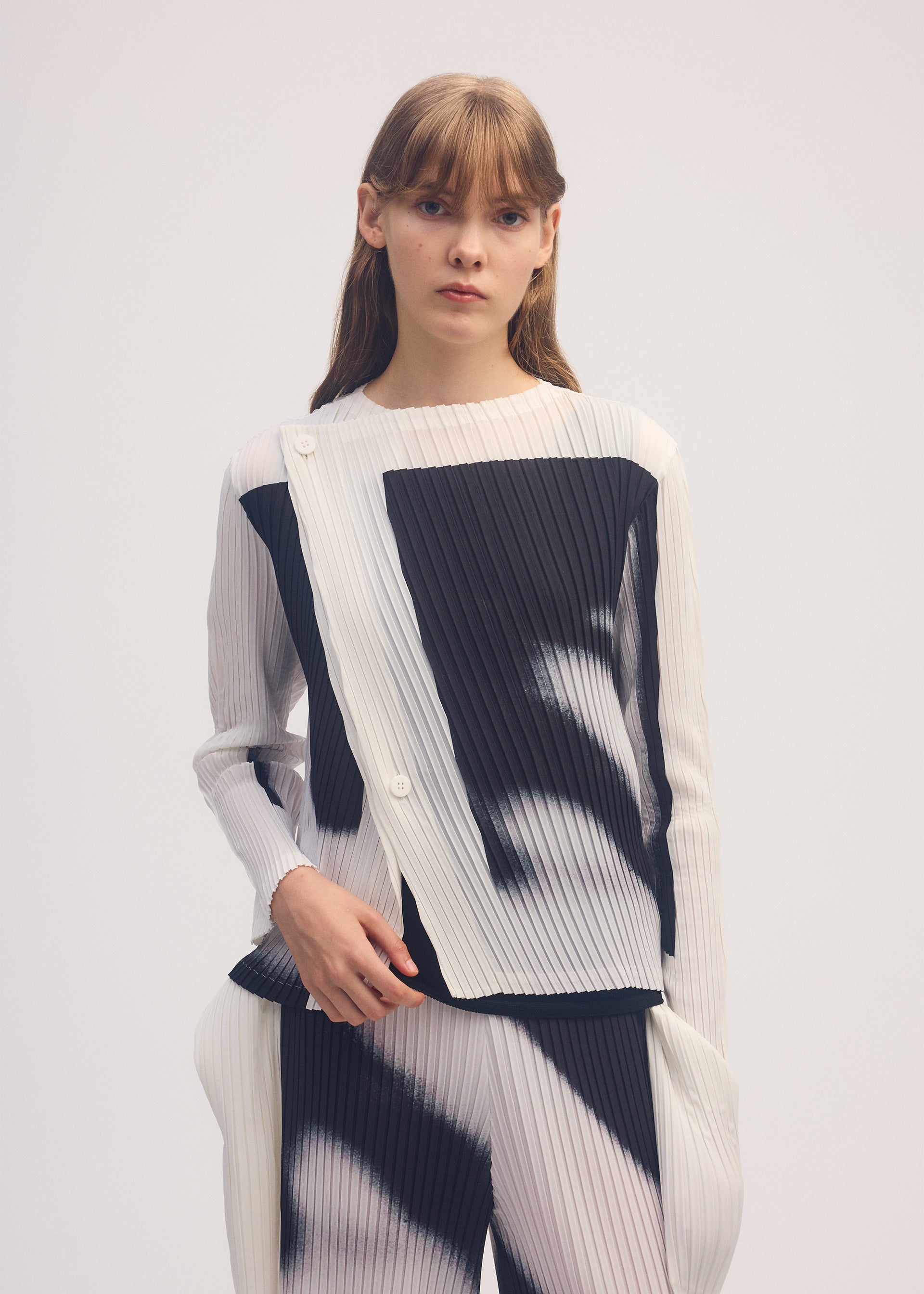 A model wears the ISSEY MIYAKE SHADOW STUDY PLEATS cardigan.