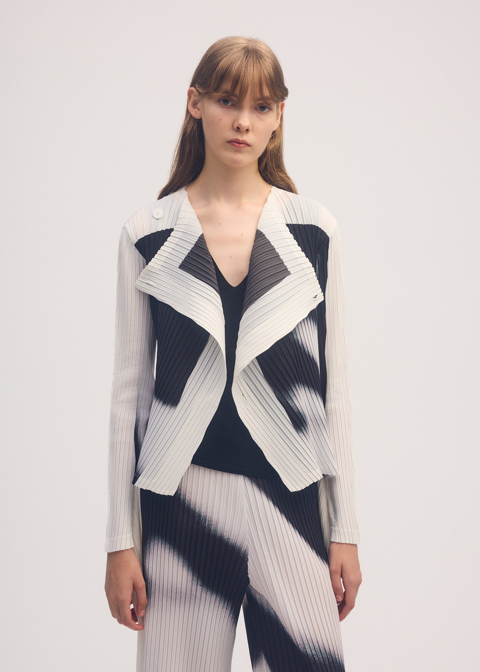 A model wears the ISSEY MIYAKE SHADOW STUDY PLEATS cardigan.