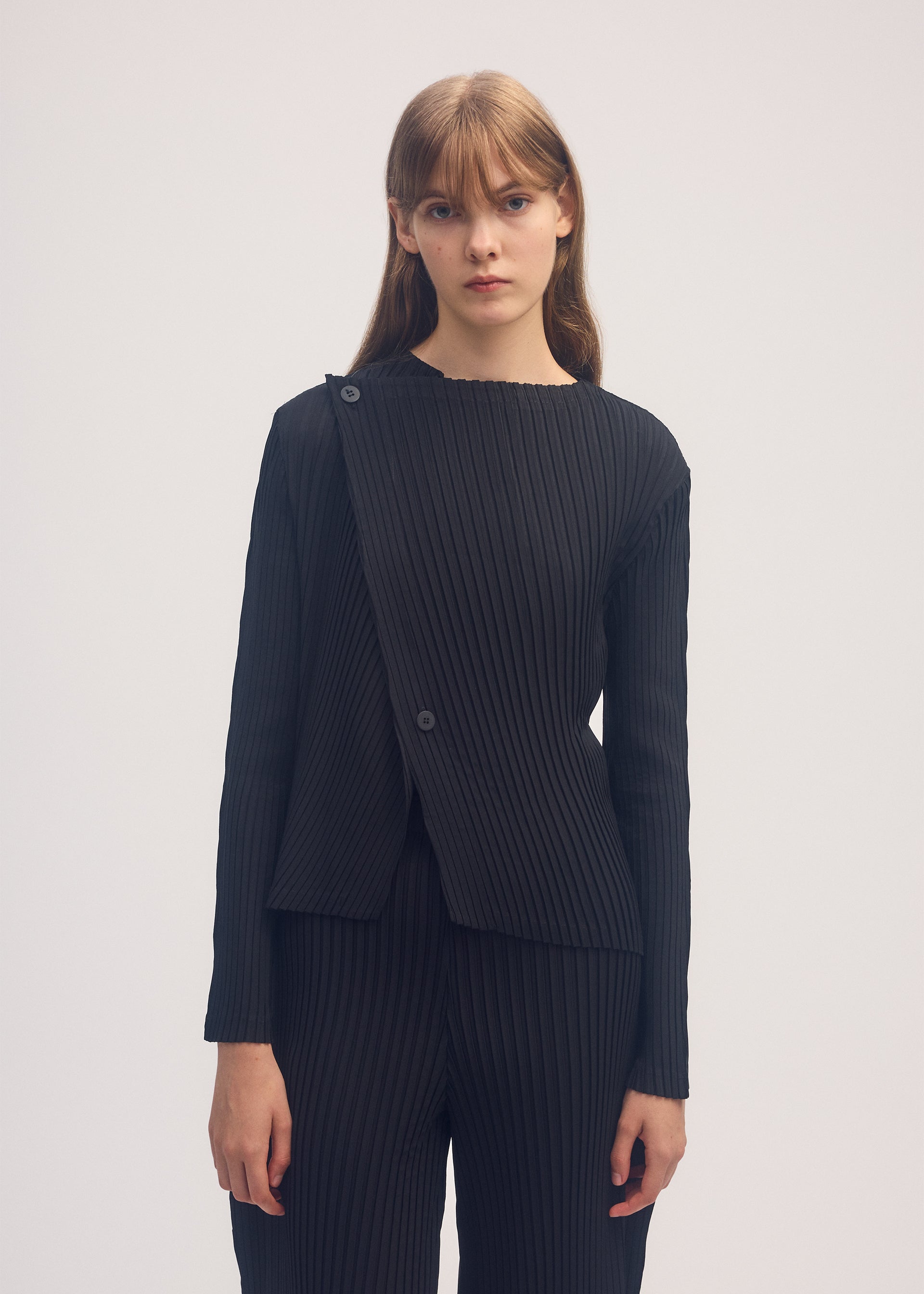 A model wears the ISSEY MIYAKE SHADOW STUDY PLEATS SOLID cardigan.
