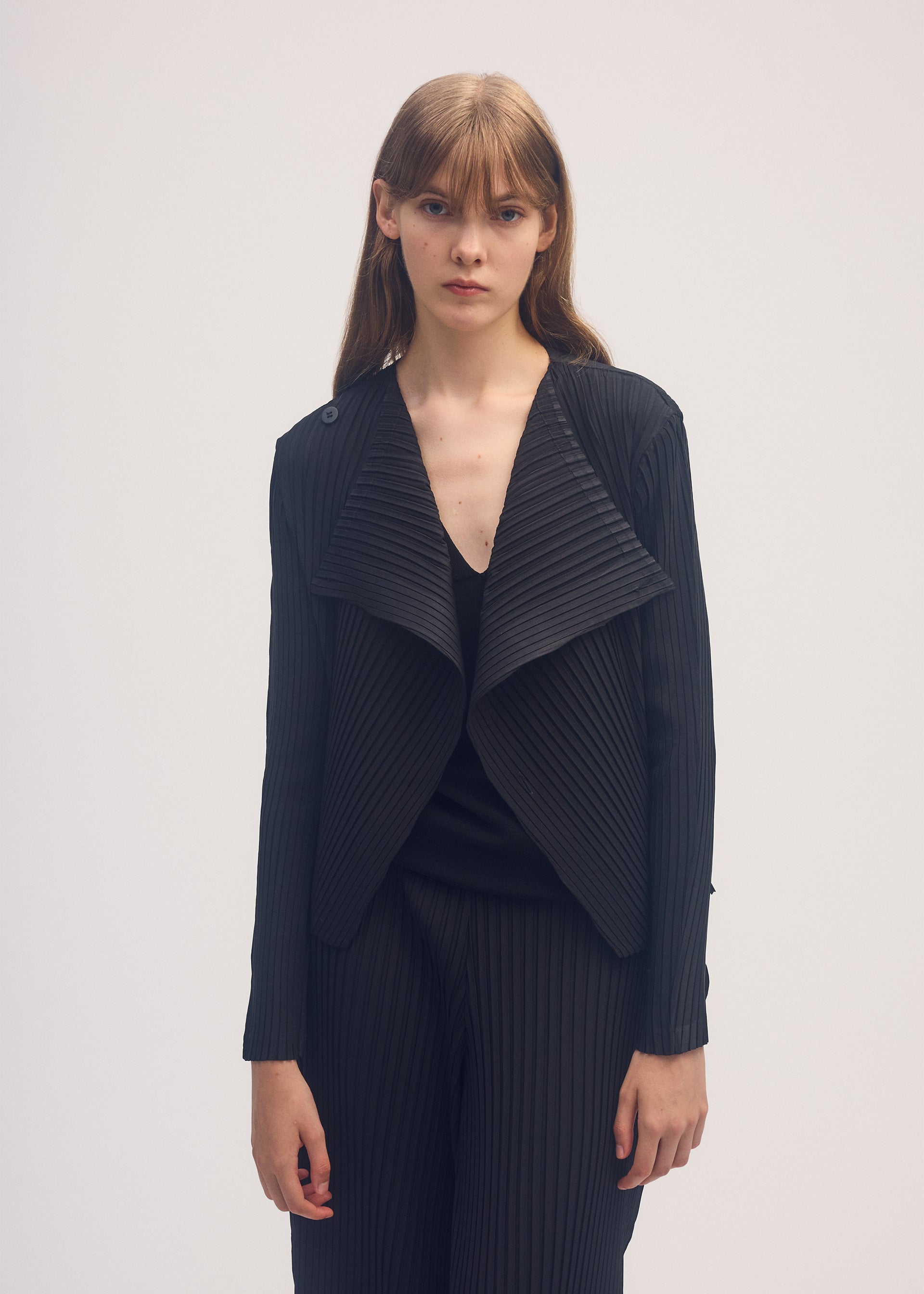 A model wears the ISSEY MIYAKE SHADOW STUDY PLEATS SOLID cardigan.