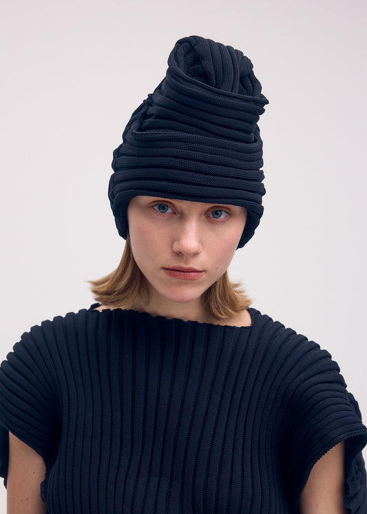 A model wears the ISSEY MIYAKE KNIT (AS IT IS) ACC hat.