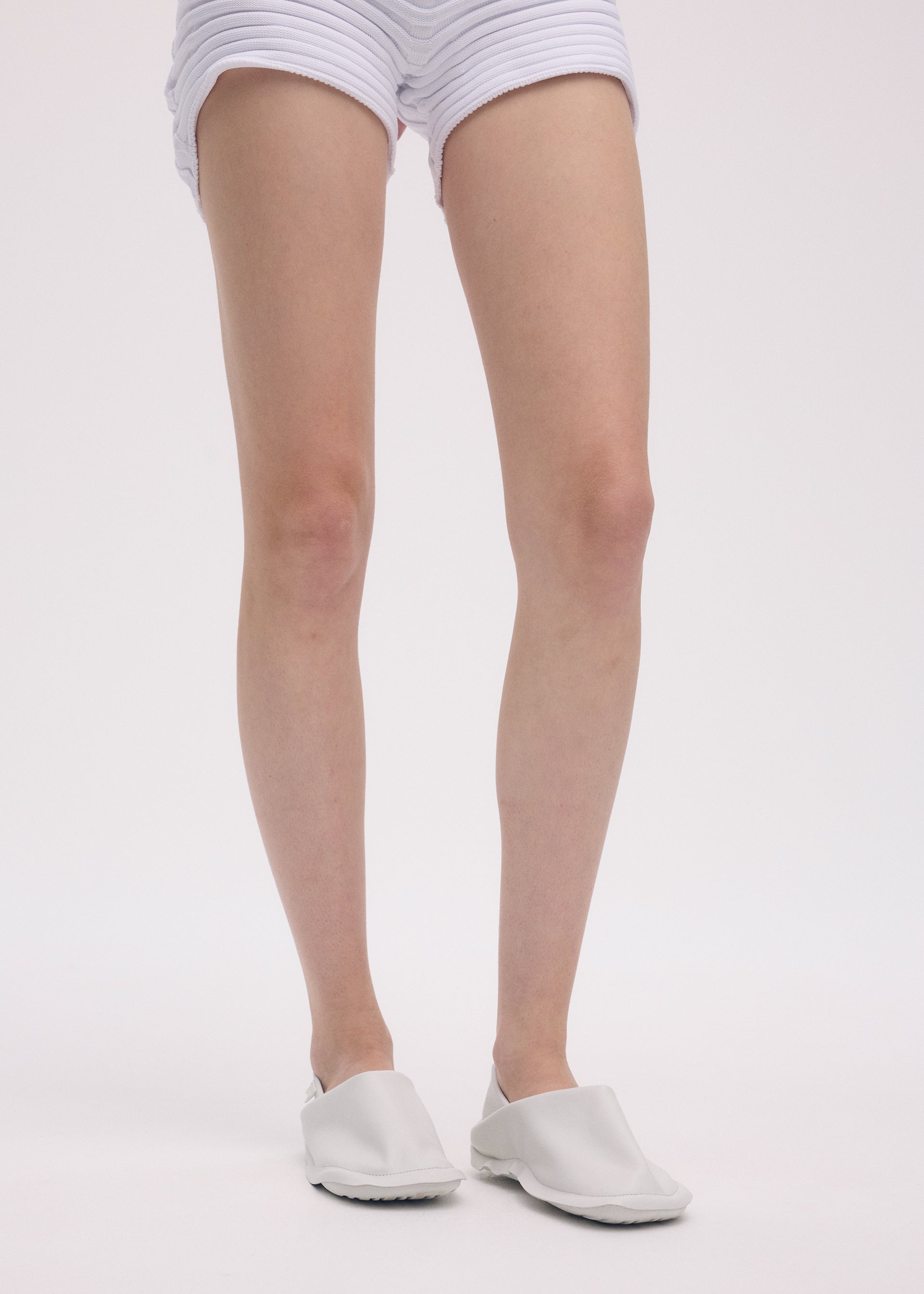 A model wears the ISSEY MIYAKE PEU FORM shoes.
