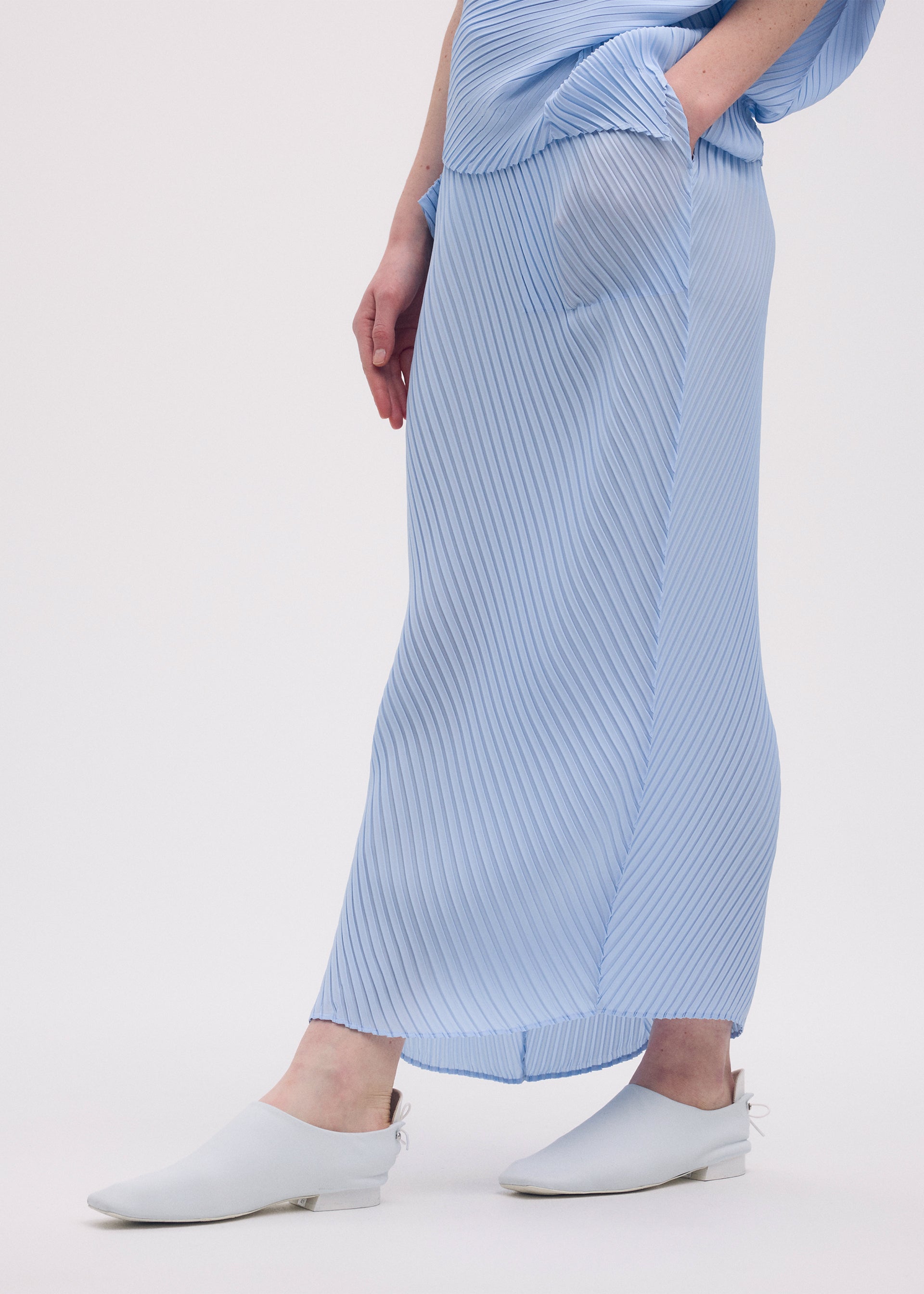 A model wears the ISSEY MIYAKE SOFT FOLD PLEATS skirt.