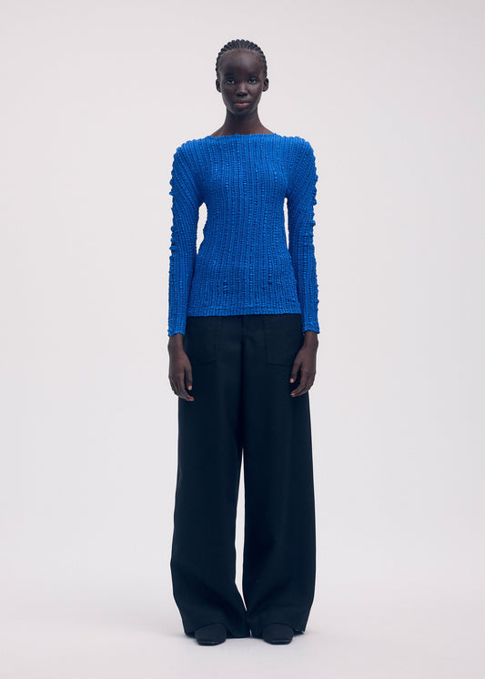 A model wears the ISSEY MIYAKE JELLYFISH PLEATS shirt.