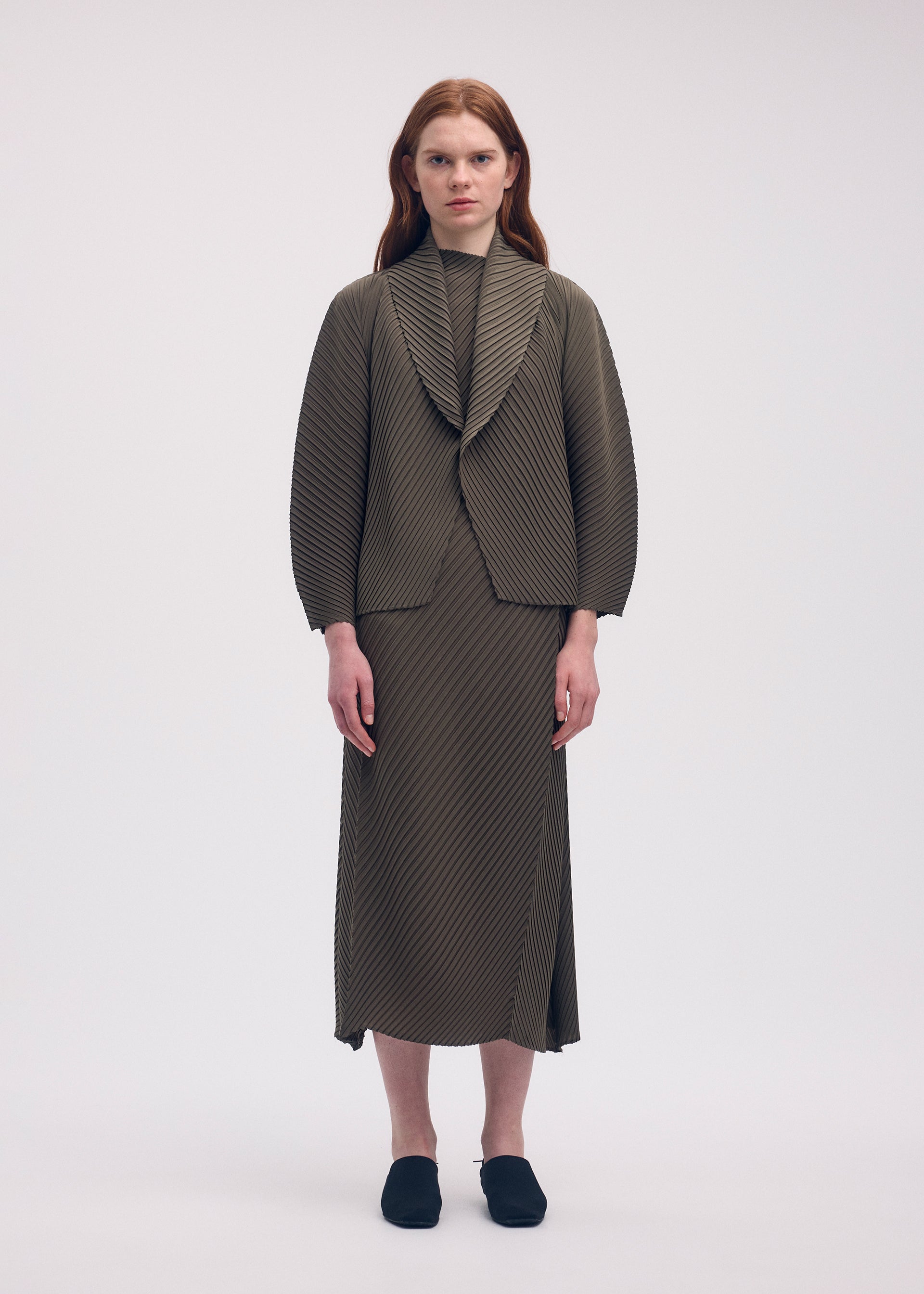 A model wears the ISSEY MIYAKE SOFT FOLD PLEATS cardigan.