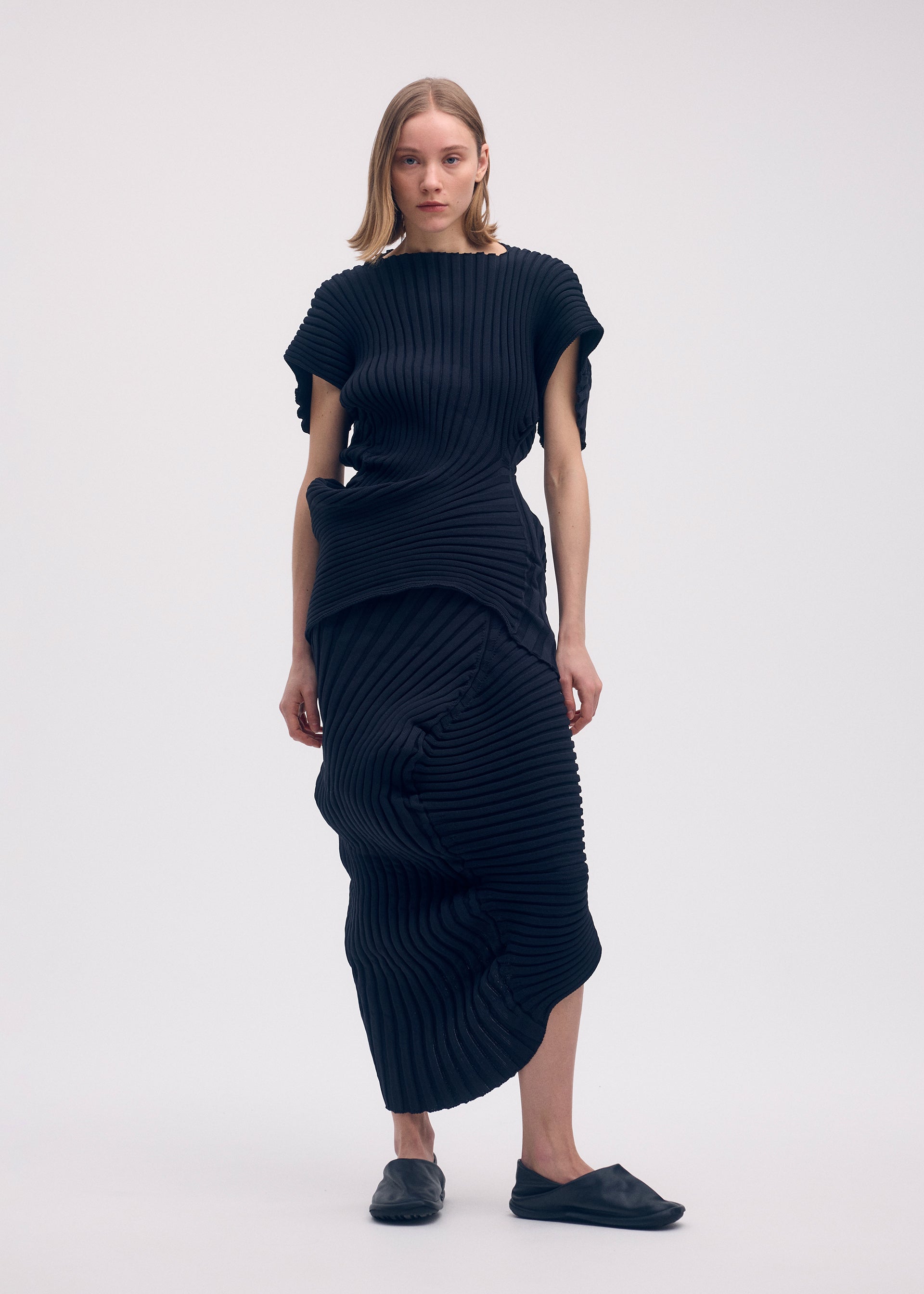 A model wears the ISSEY MIYAKE KNIT (AS IT IS) skirt.