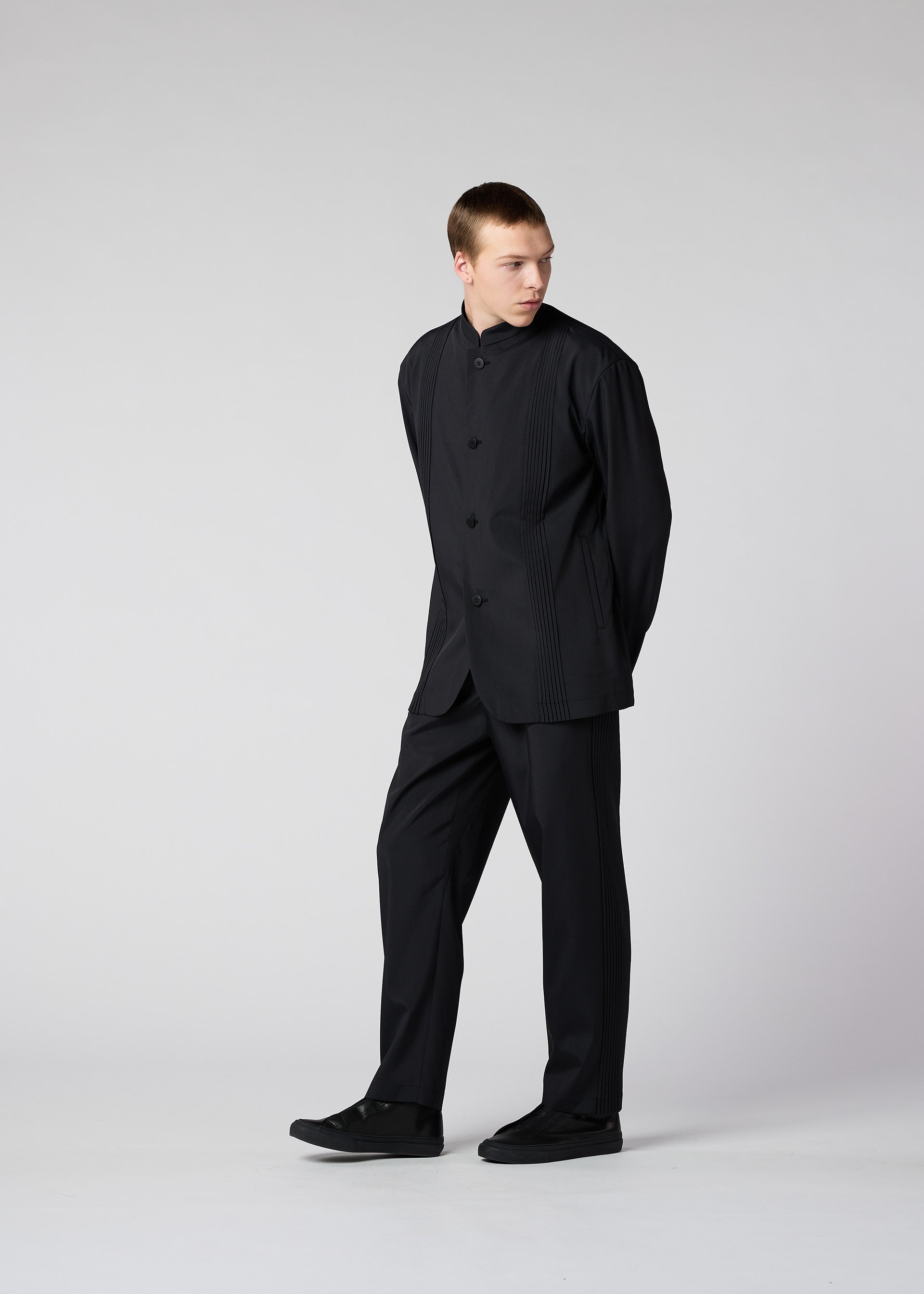 A model wears the IM MEN AIR PLEATS trousers.