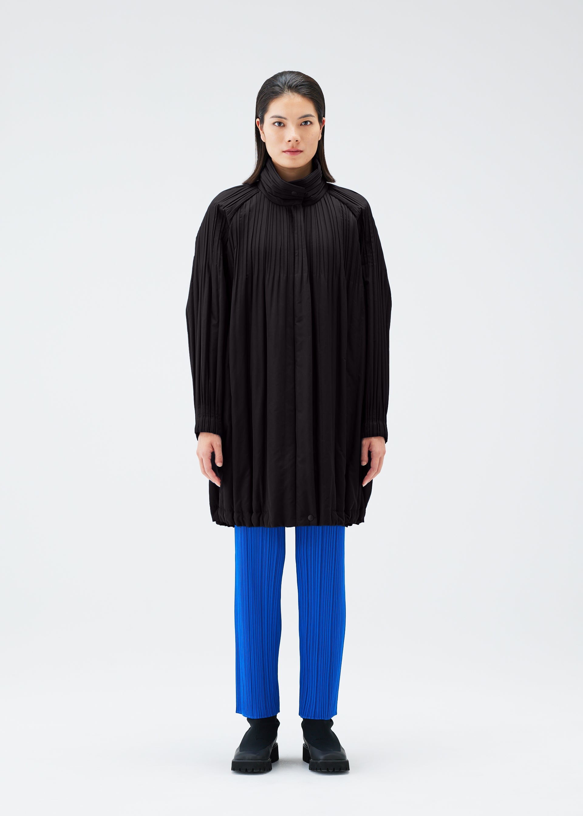 A model wears the PLEATS PLEASE ISSEY MIYAKE PADDED PLEATS COAT coat.
