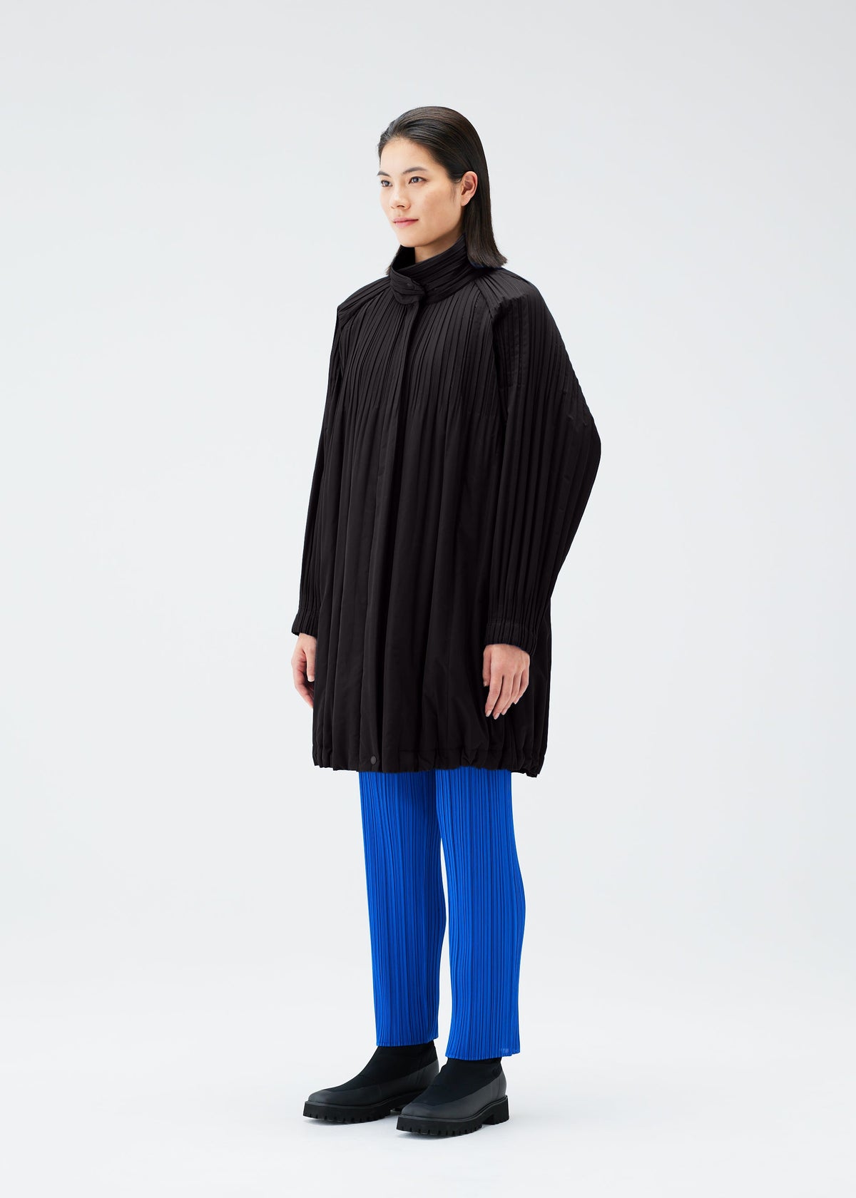 A model wears the PLEATS PLEASE ISSEY MIYAKE PADDED PLEATS COAT coat.