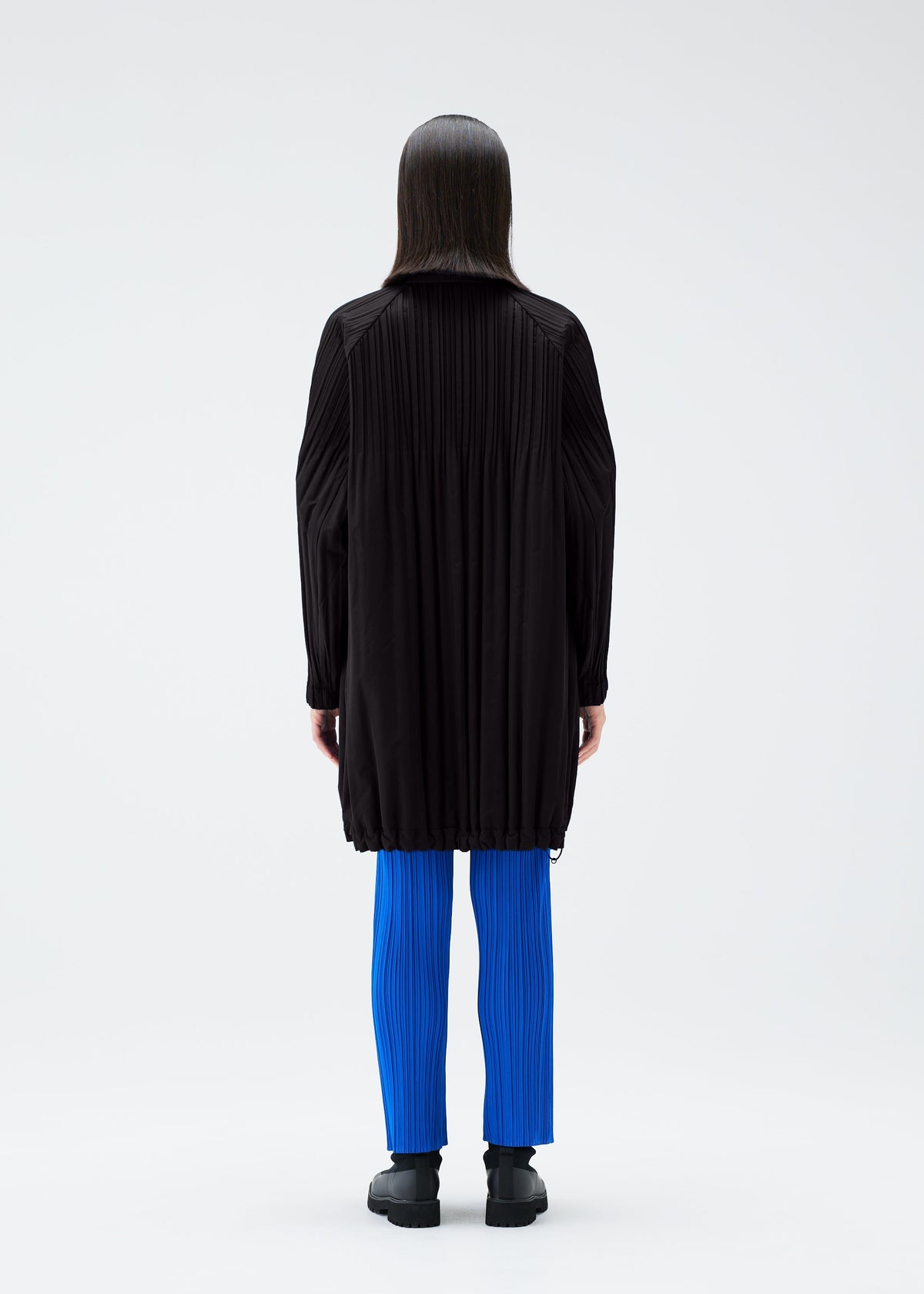 A model wears the PLEATS PLEASE ISSEY MIYAKE PADDED PLEATS COAT coat.