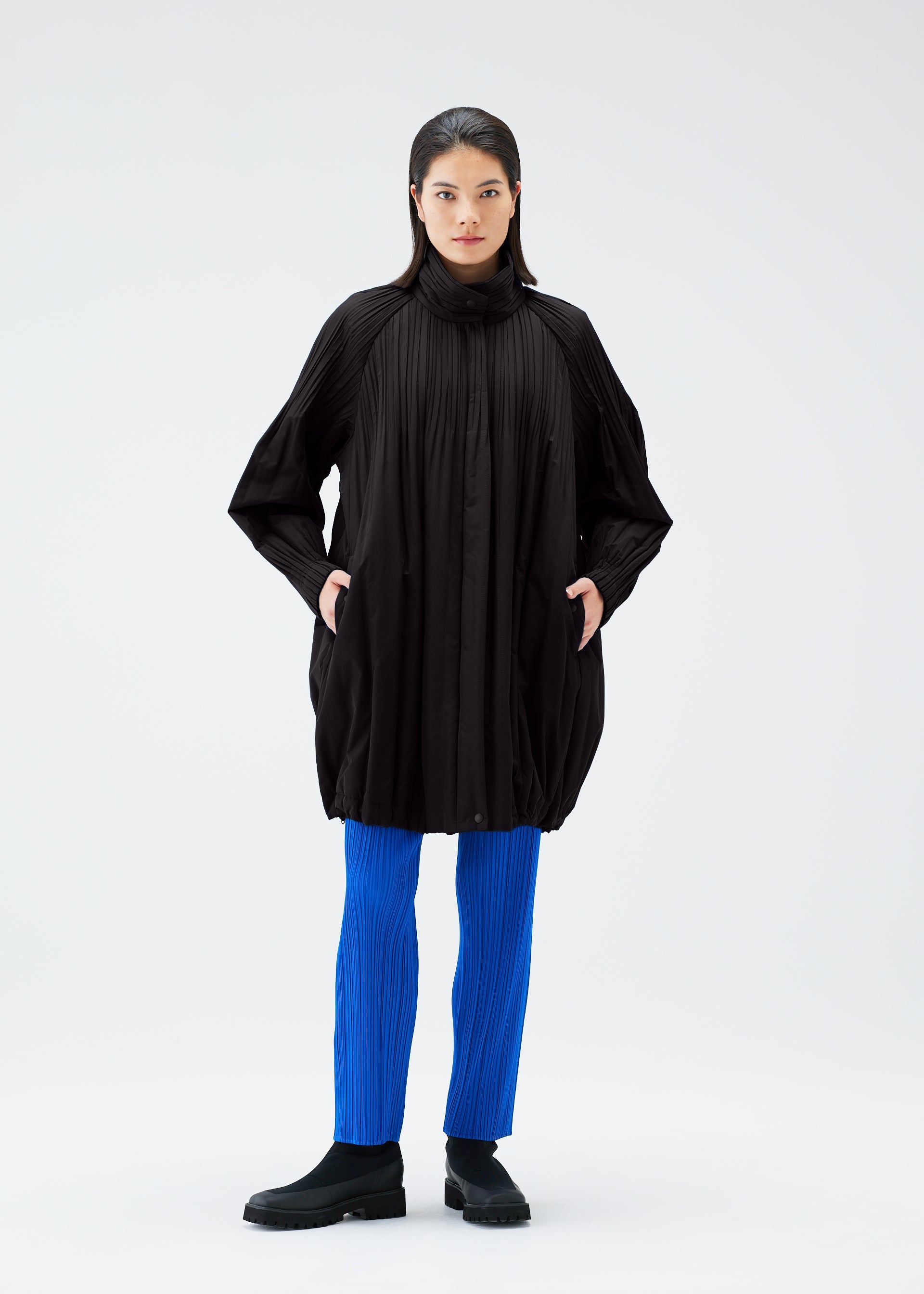A model wears the PLEATS PLEASE ISSEY MIYAKE PADDED PLEATS COAT coat.