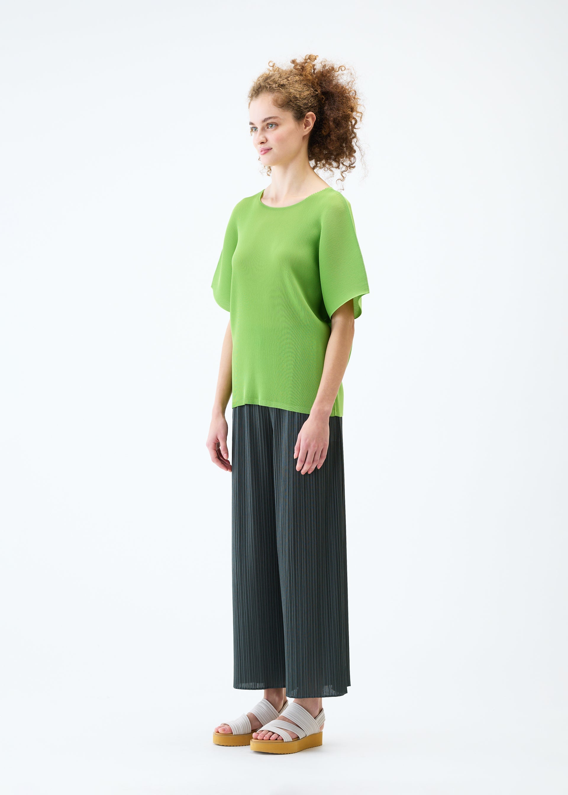A model wears the PLEATS PLEASE ISSEY MIYAKE MIST JUNE top.