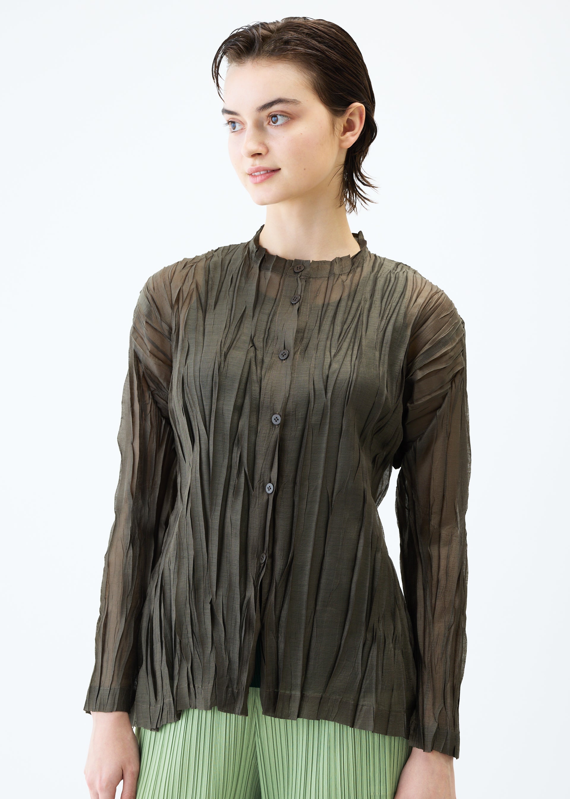 A model wears the PLEATS PLEASE ISSEY MIYAKE SHEER TWIST cardigan.