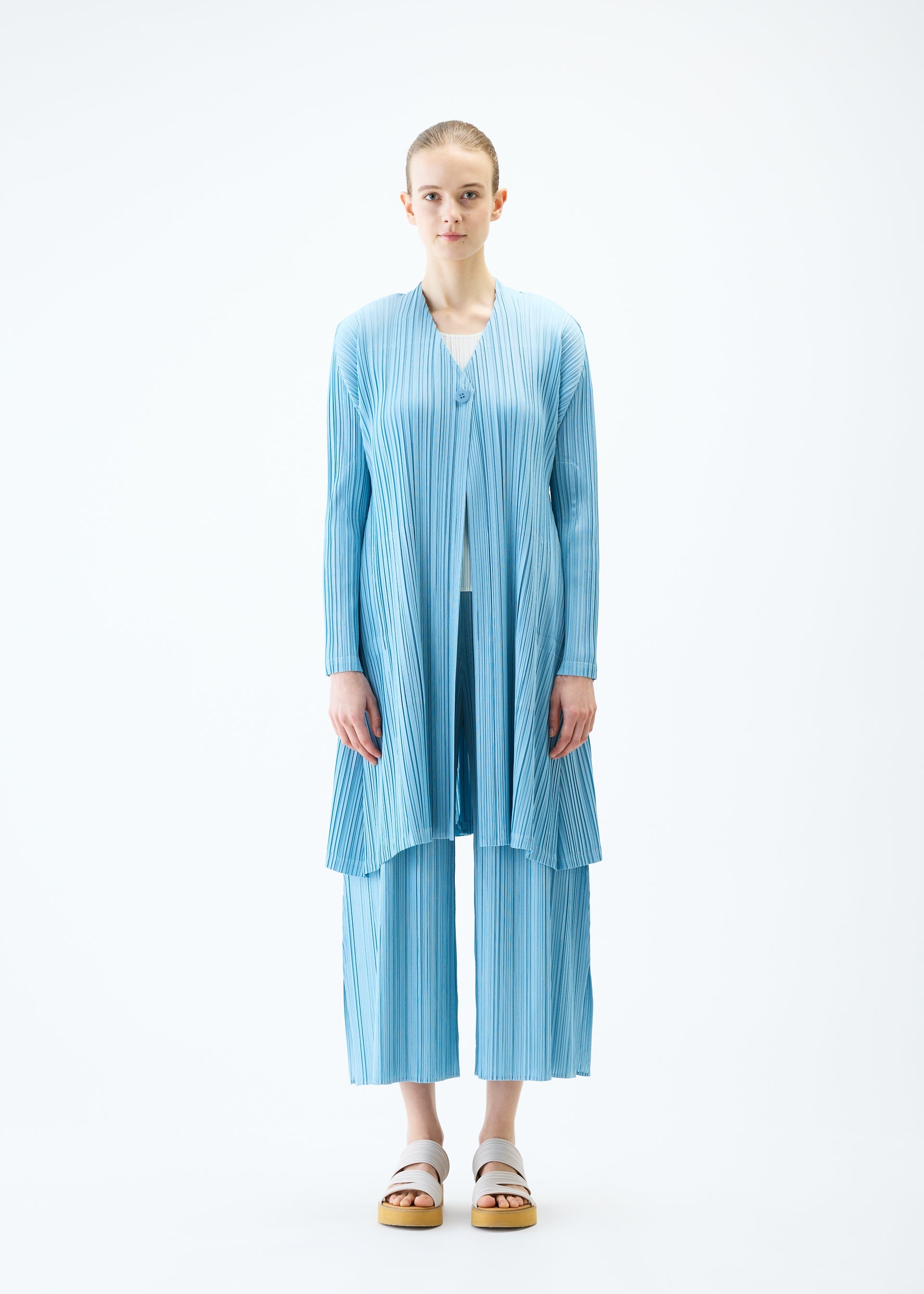 A model wears the PLEATS PLEASE ISSEY MIYAKE MELLOW PLEATS coat.