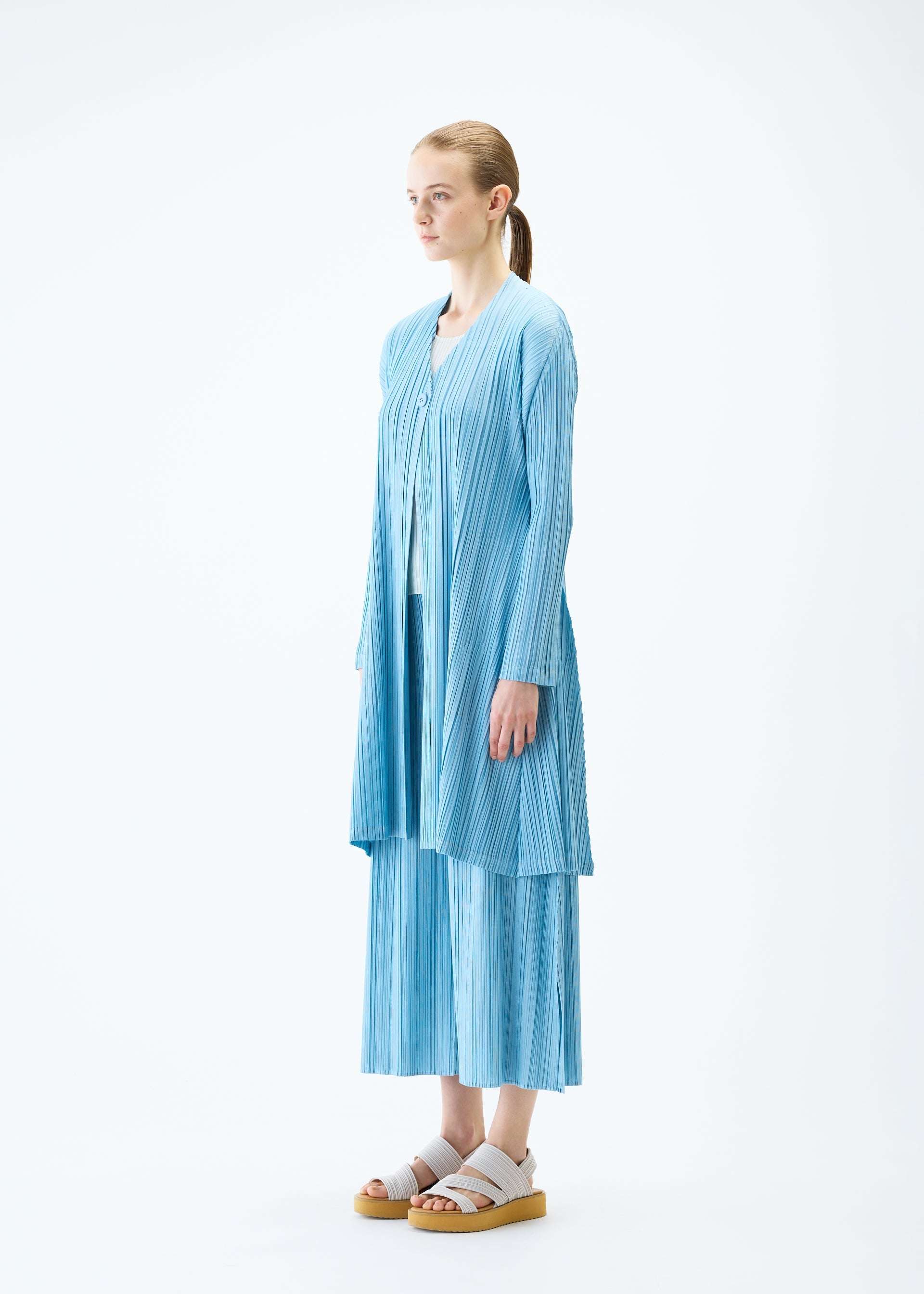 A model wears the PLEATS PLEASE ISSEY MIYAKE MELLOW PLEATS coat.