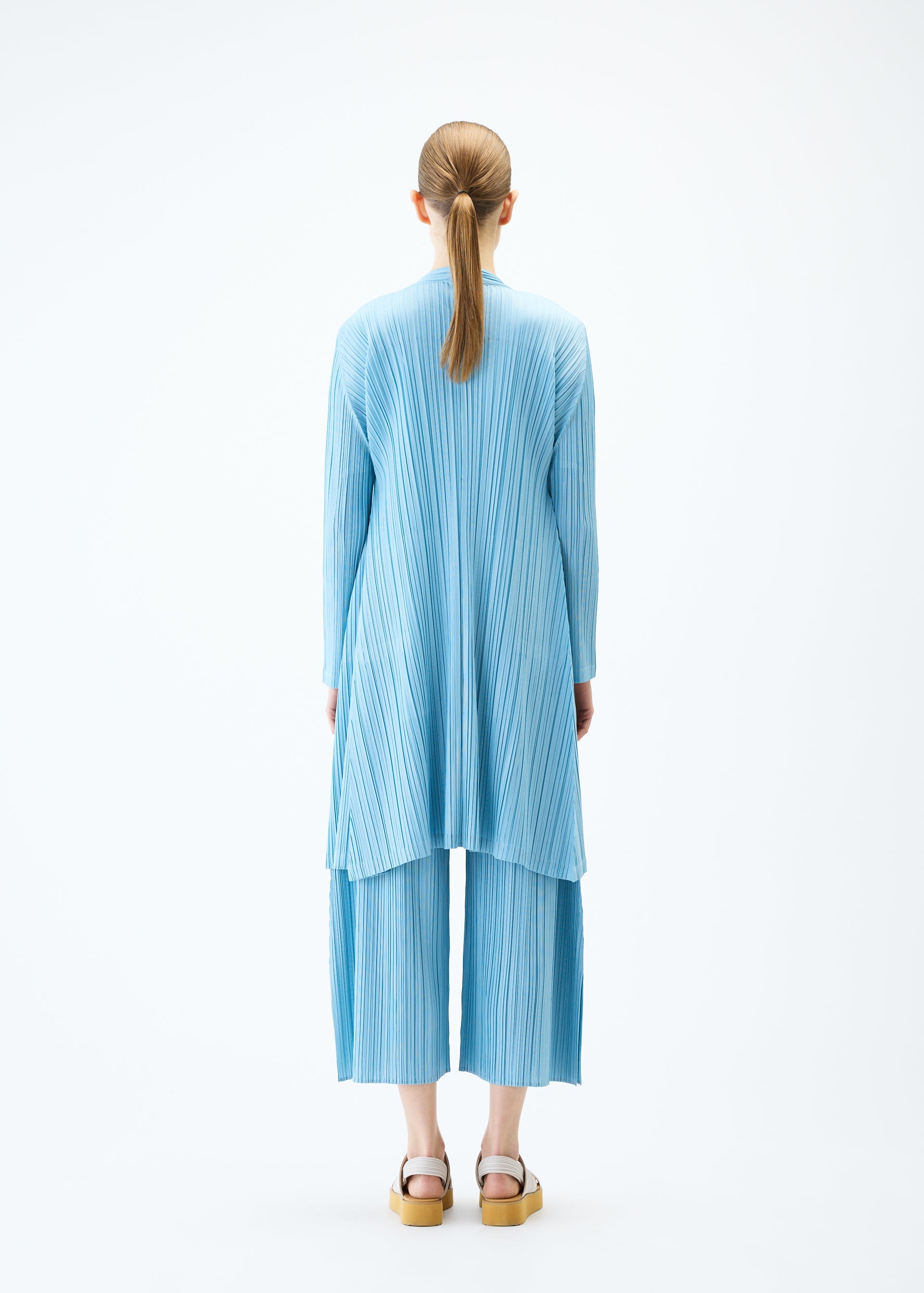 A model wears the PLEATS PLEASE ISSEY MIYAKE MELLOW PLEATS coat.