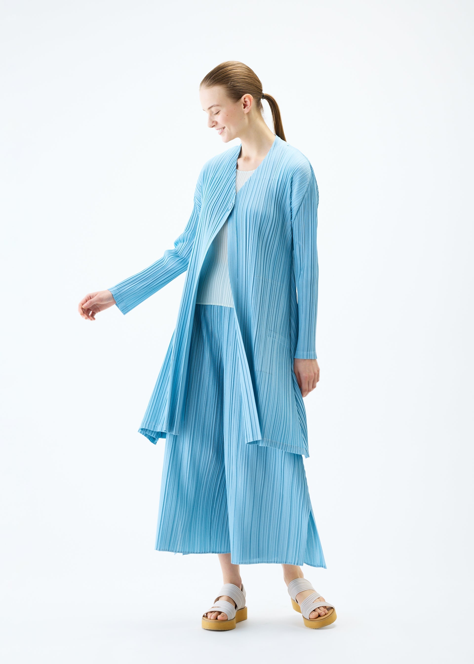 A model wears the PLEATS PLEASE ISSEY MIYAKE MELLOW PLEATS coat.