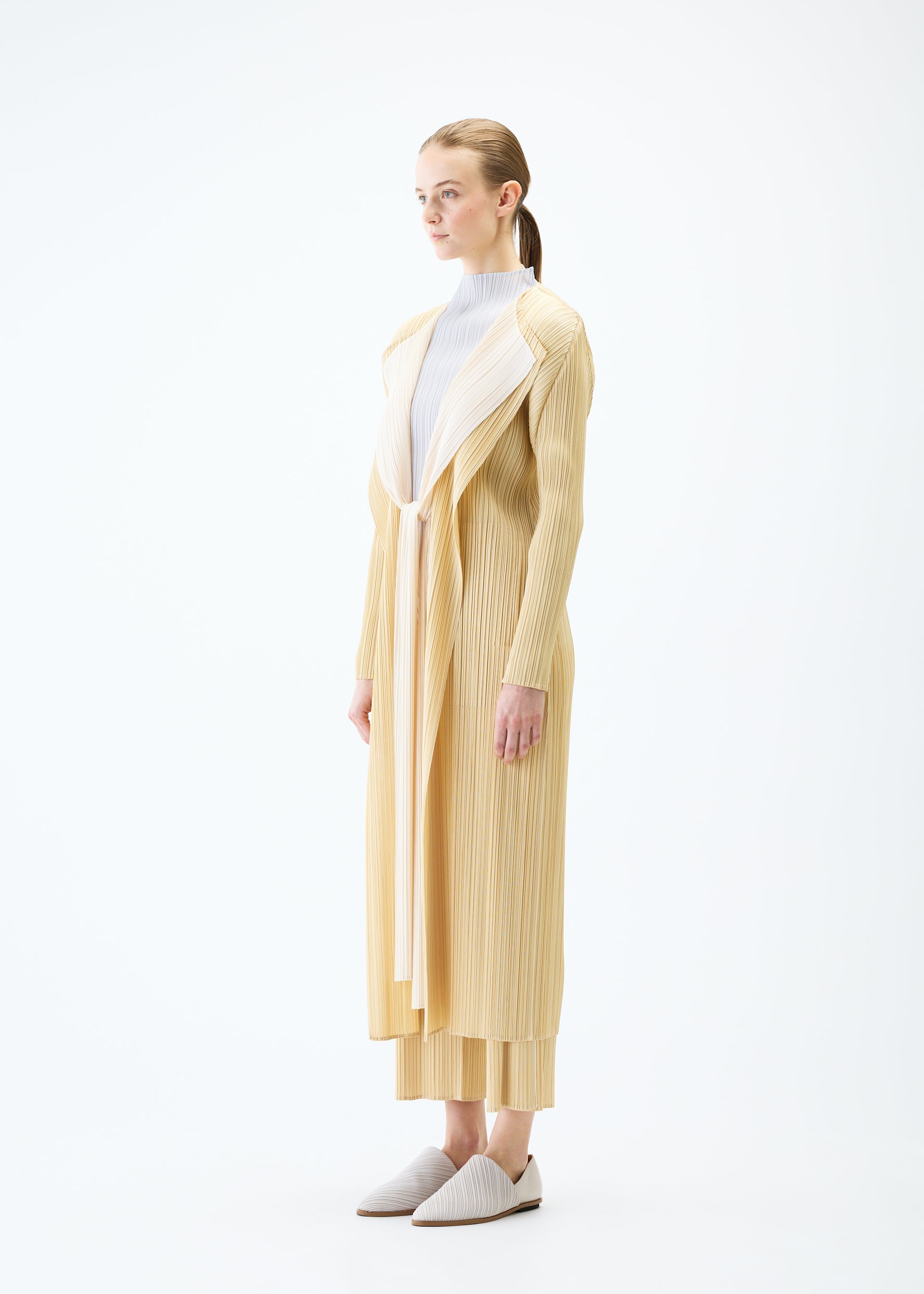 A model wears the PLEATS PLEASE ISSEY MIYAKE MERRY BICOLOR coat.