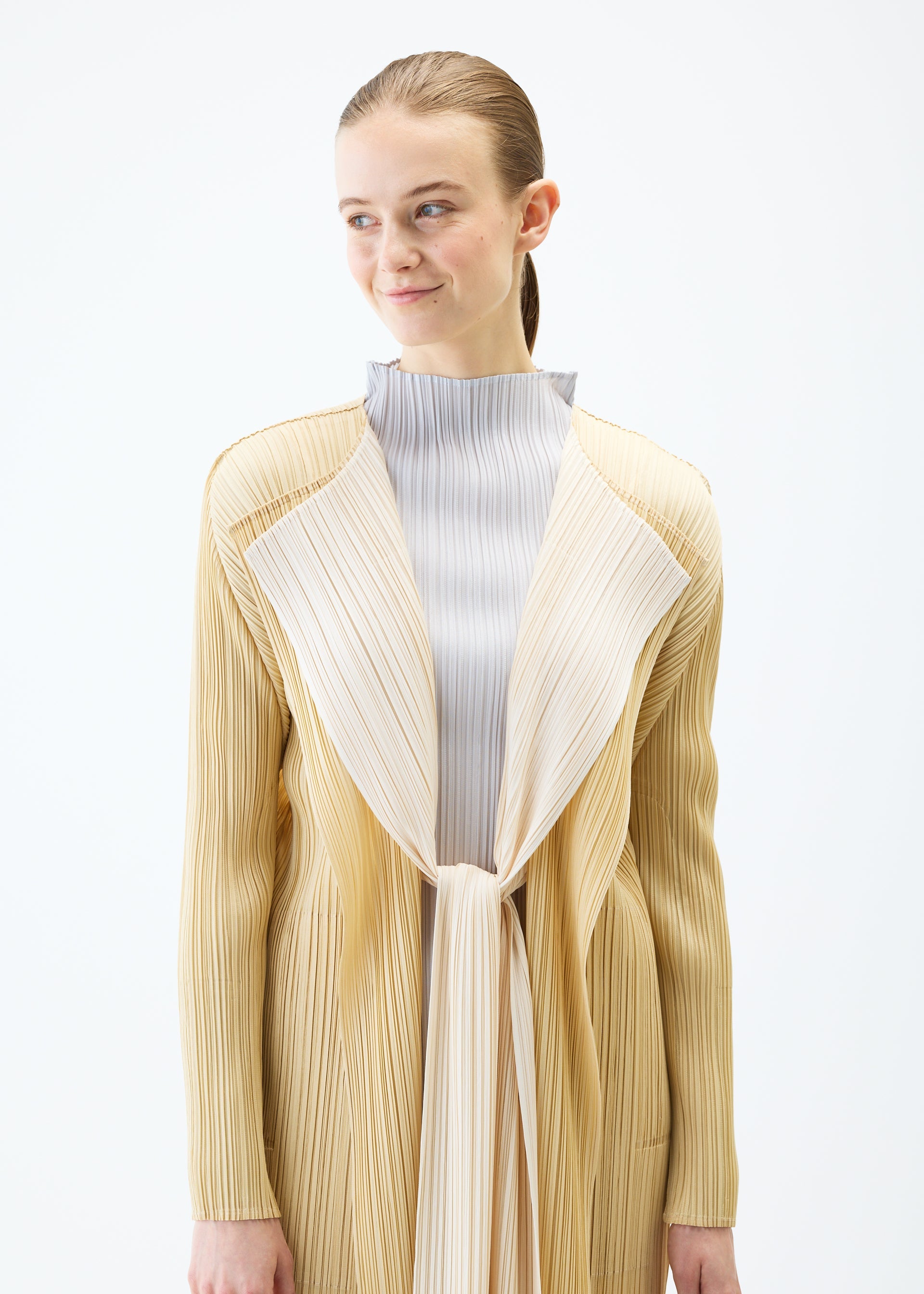 A model wears the PLEATS PLEASE ISSEY MIYAKE MERRY BICOLOR coat.