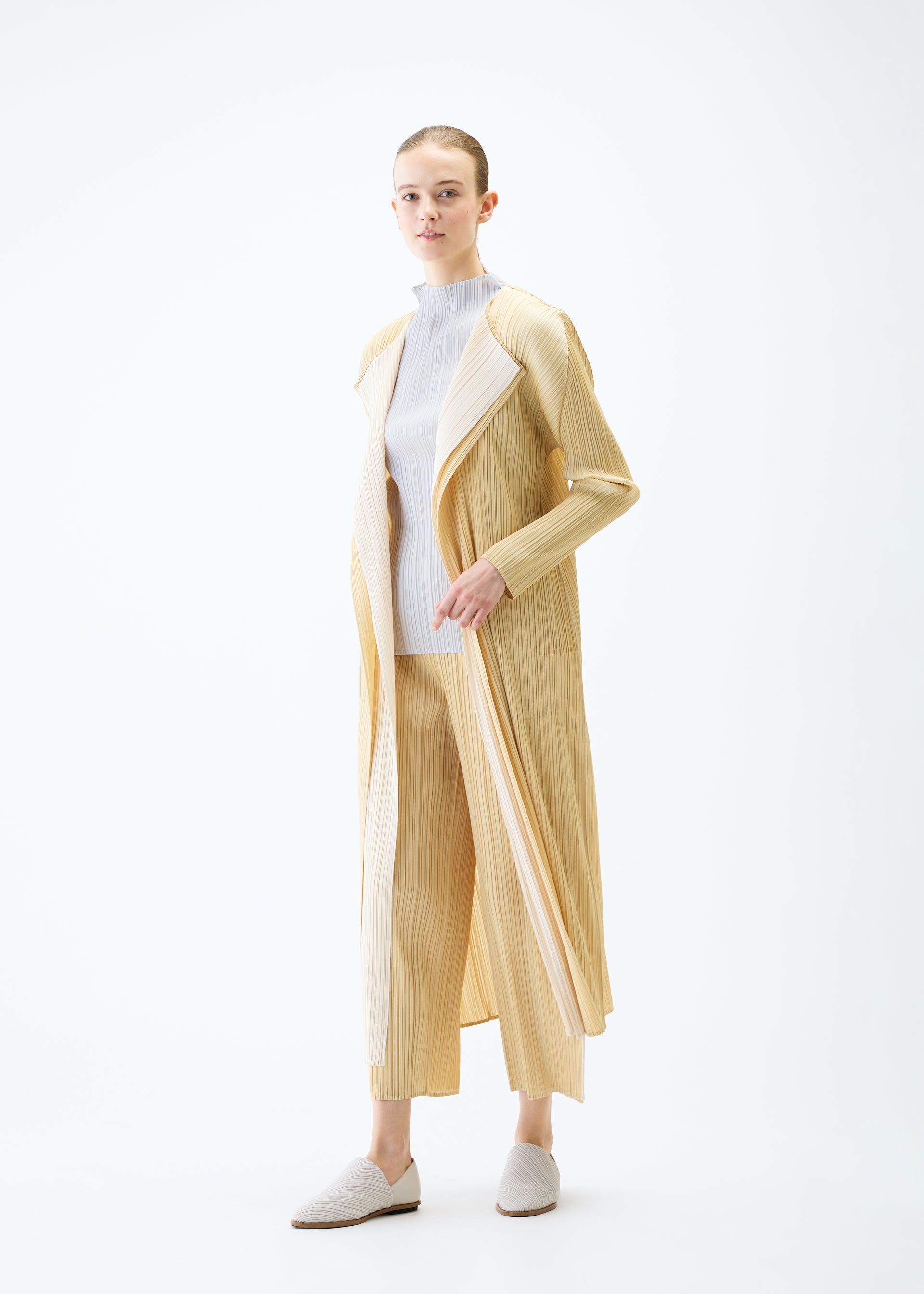A model wears the PLEATS PLEASE ISSEY MIYAKE MERRY BICOLOR coat.