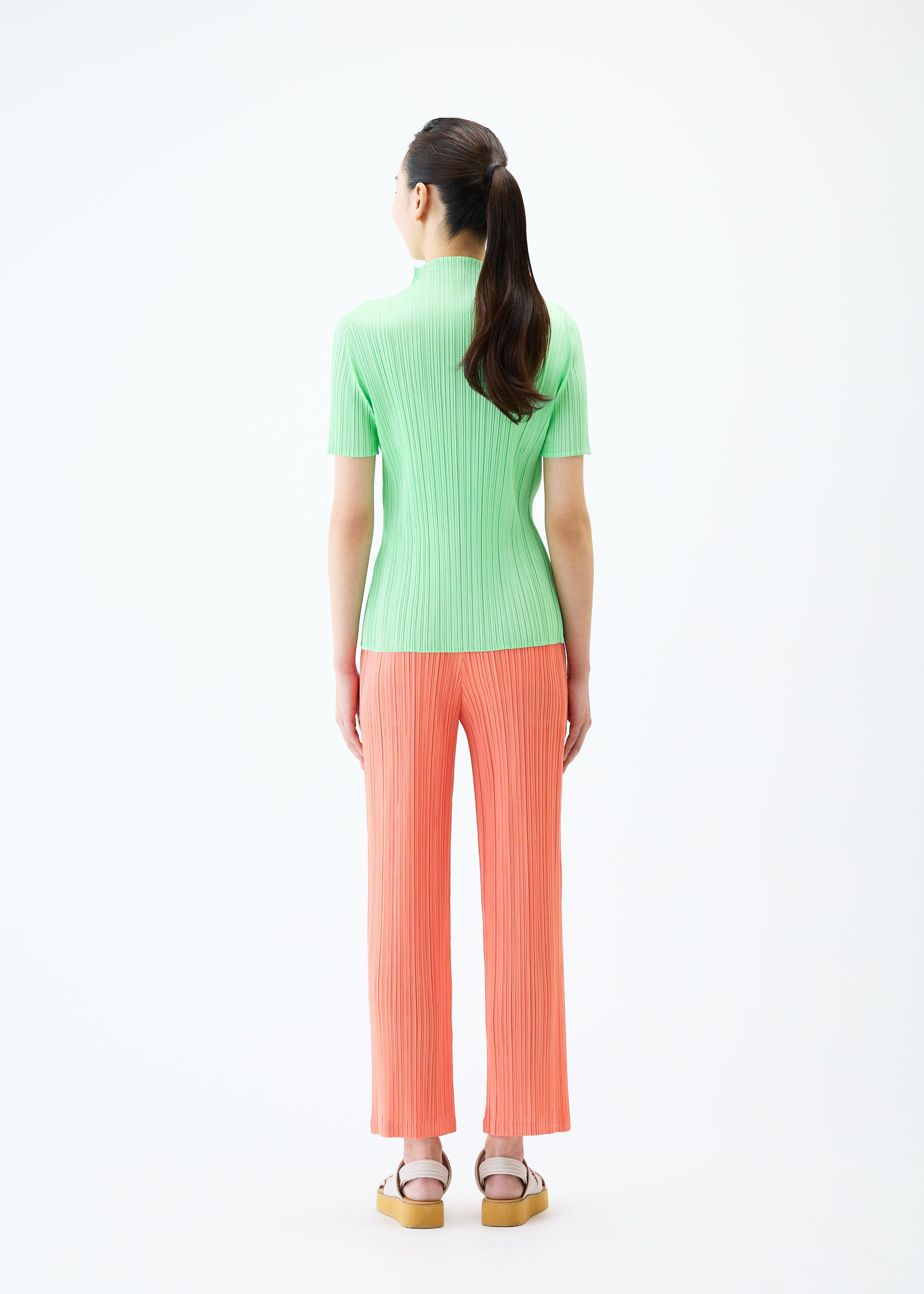 A model wears the PLEATS PLEASE ISSEY MIYAKE MONTHLY COLORS MAY trousers.