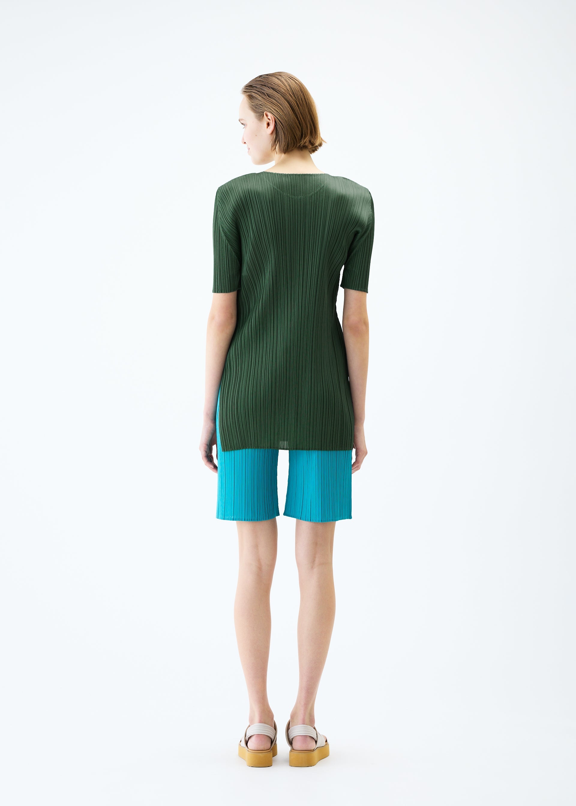 A model wears the PLEATS PLEASE ISSEY MIYAKE MONTHLY COLORS : JUNE trousers.