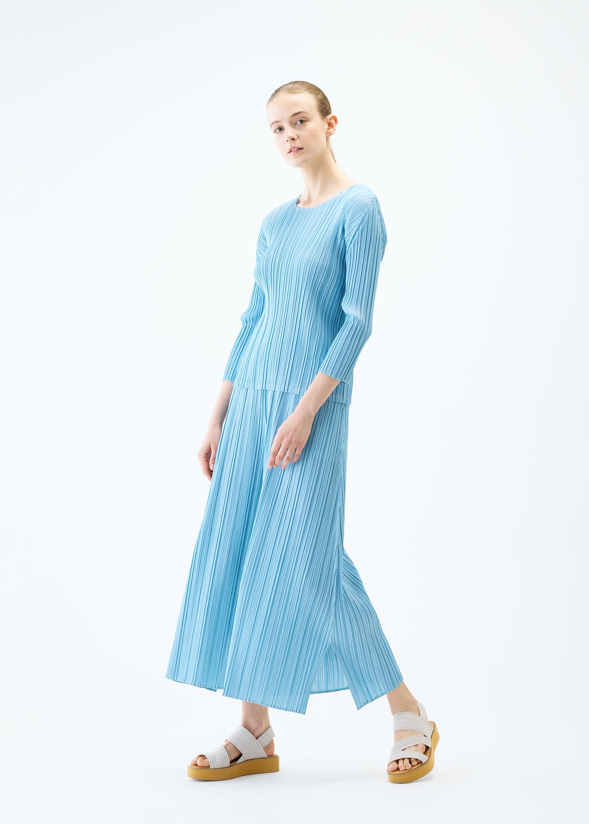 A model wears the PLEATS PLEASE ISSEY MIYAKE MELLOW PLEATS trousers.