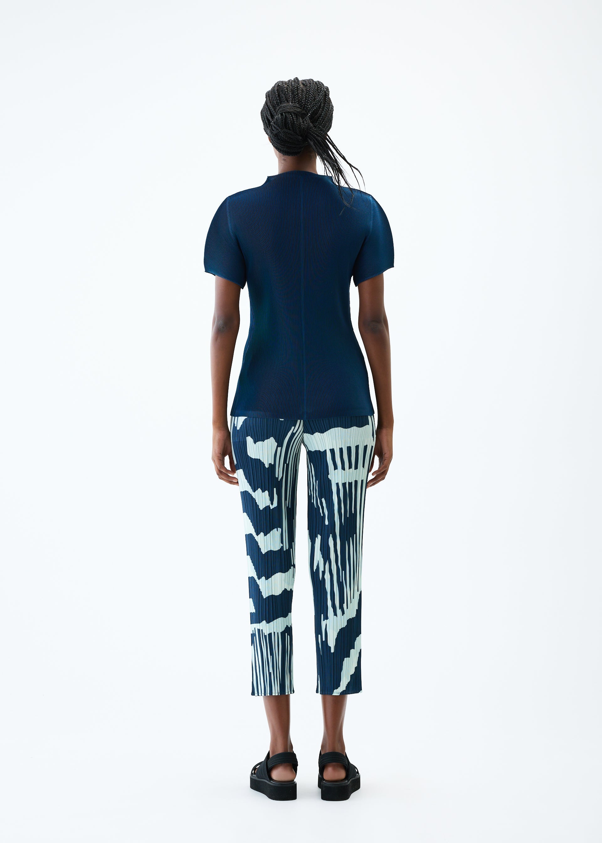 A model wears the PLEATS PLEASE ISSEY MIYAKE REFRACTION trousers.