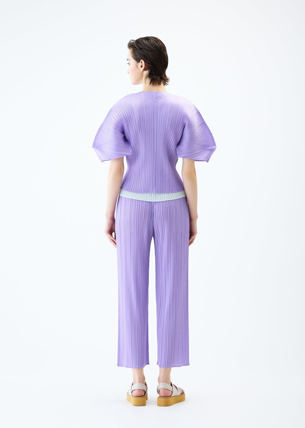 A model wears the PLEATS PLEASE ISSEY MIYAKE MONTHLY COLORS APRIL cardigan.