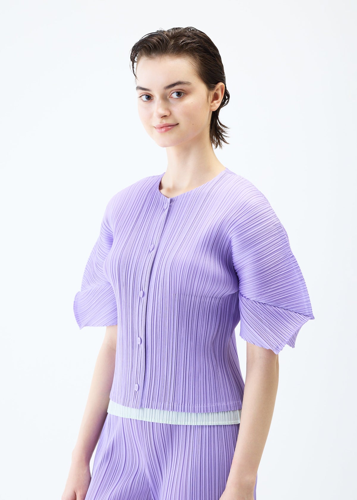 A model wears the PLEATS PLEASE ISSEY MIYAKE MONTHLY COLORS APRIL cardigan.