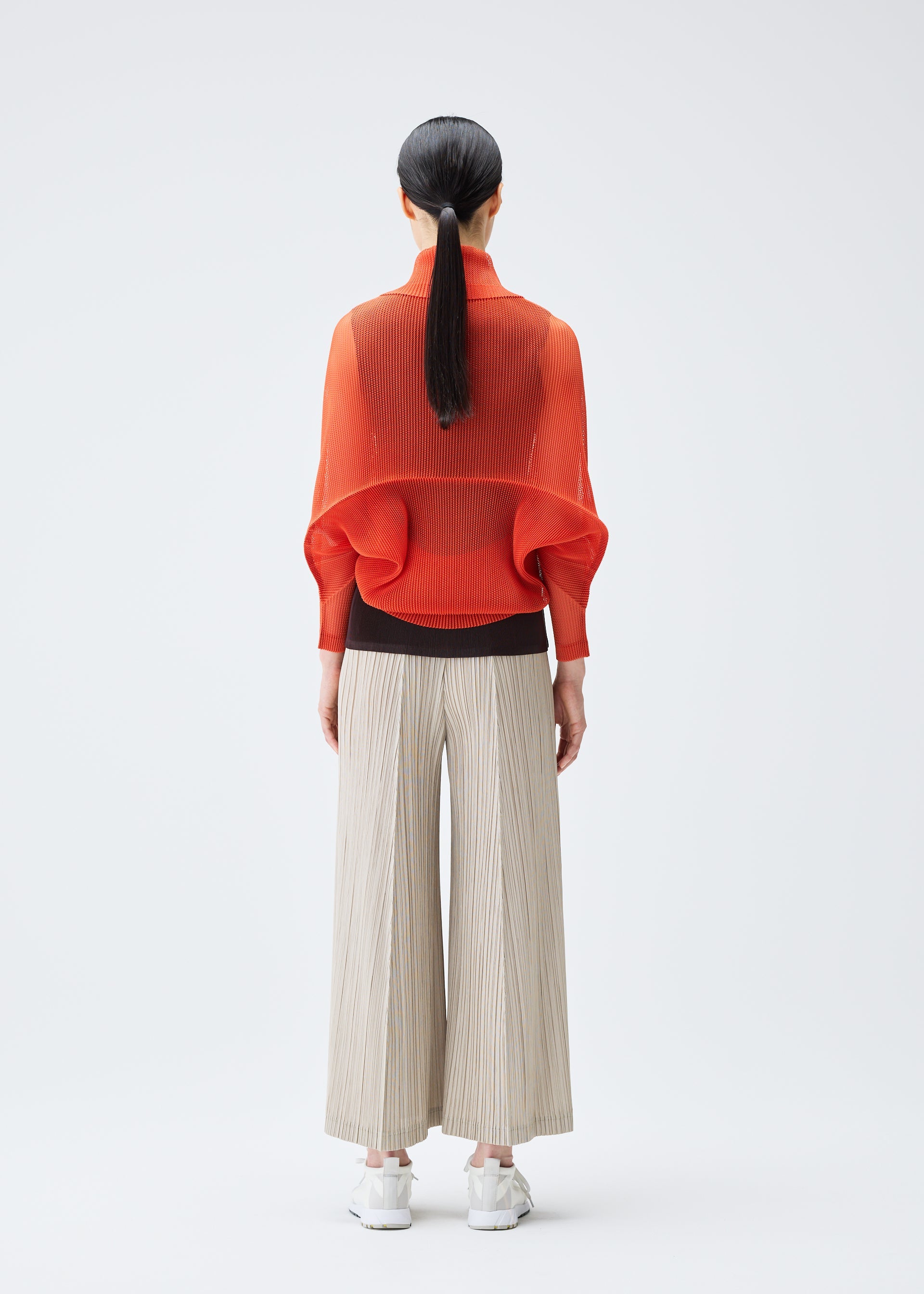 A model wears the PLEATS PLEASE ISSEY MIYAKE TATAMI JULY cardigan.