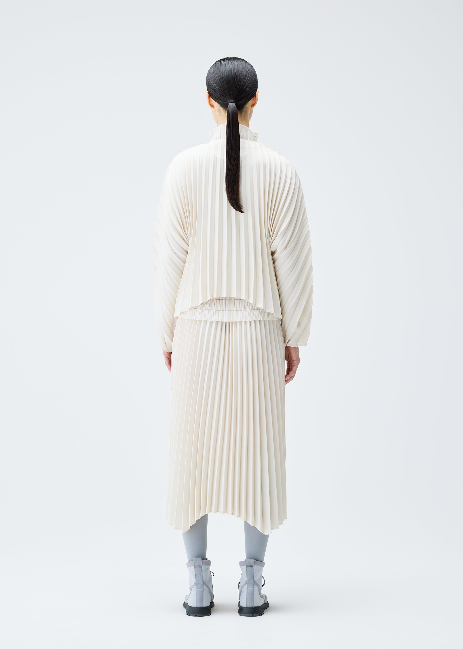 A model wears the PLEATS PLEASE ISSEY MIYAKE CIRCULAR cardigan.