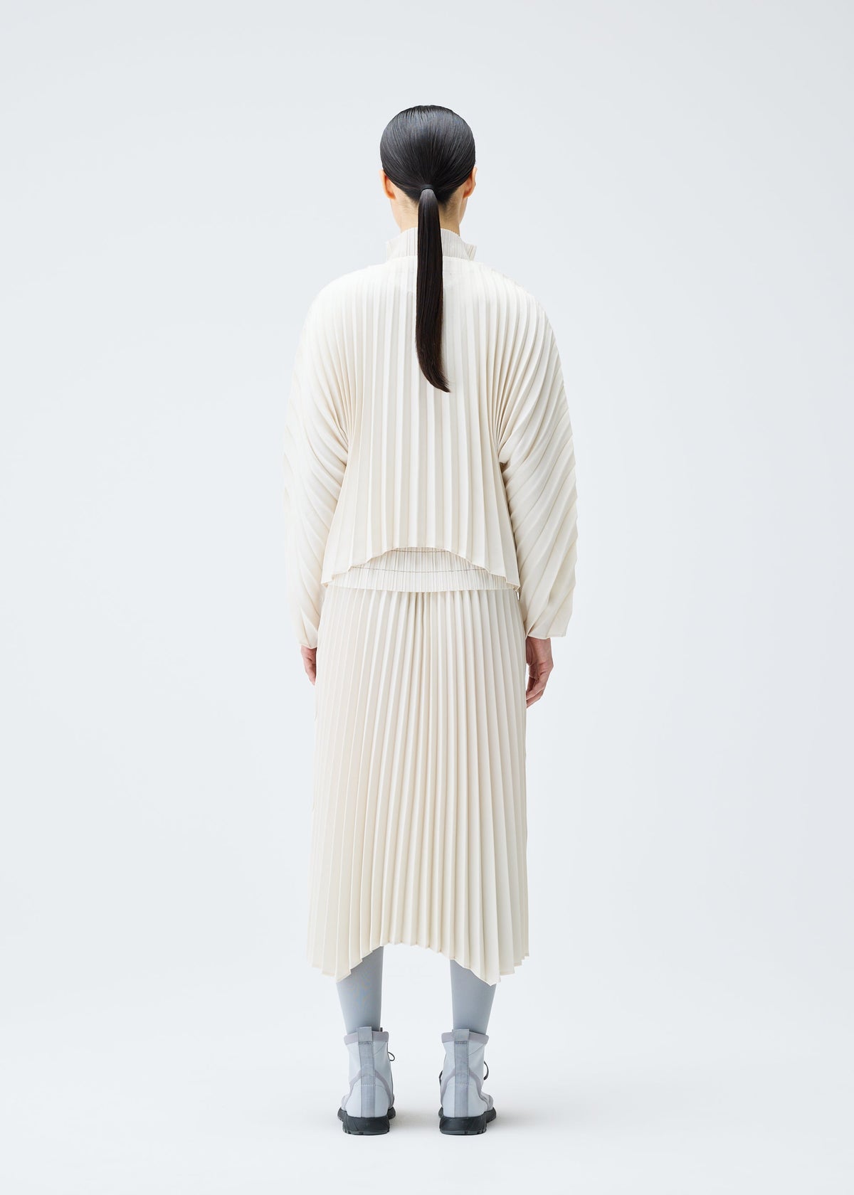 A model wears the PLEATS PLEASE ISSEY MIYAKE CIRCULAR cardigan.