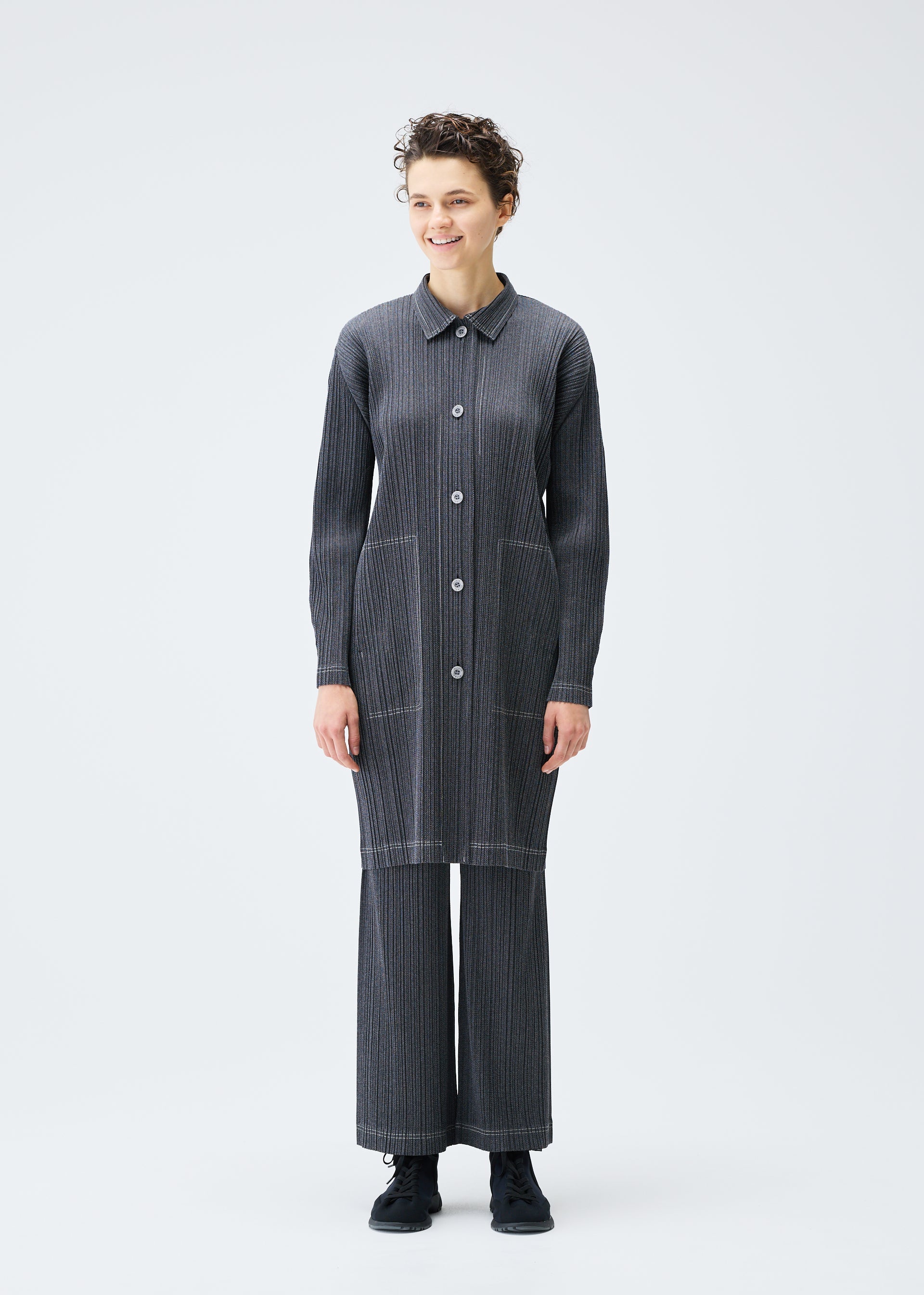 A model wears the PLEATS PLEASE ISSEY MIYAKE COTTON DENIM coat.