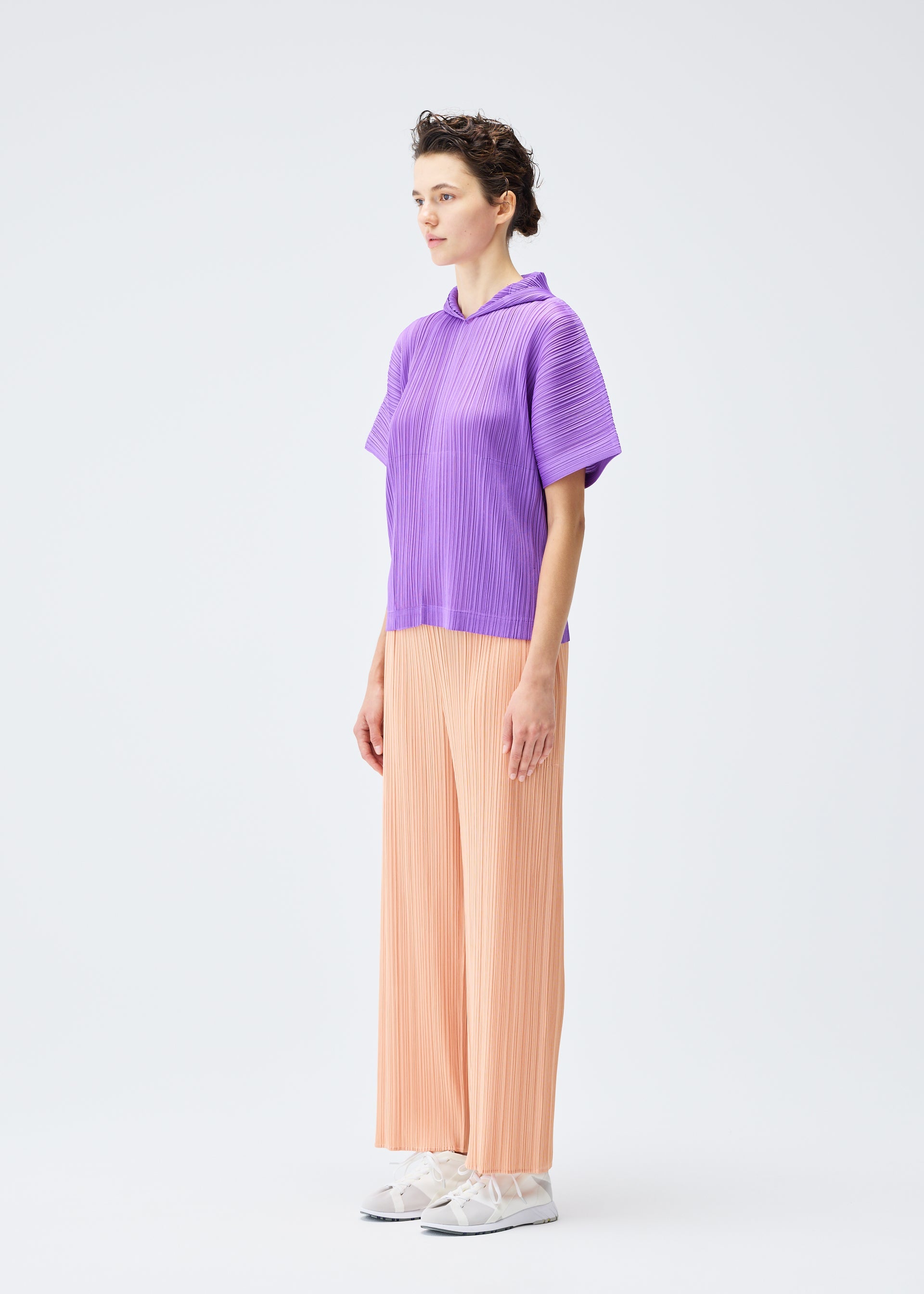 A model wears the PLEATS PLEASE ISSEY MIYAKE MONTHLY COLORS AUGUST trousers.