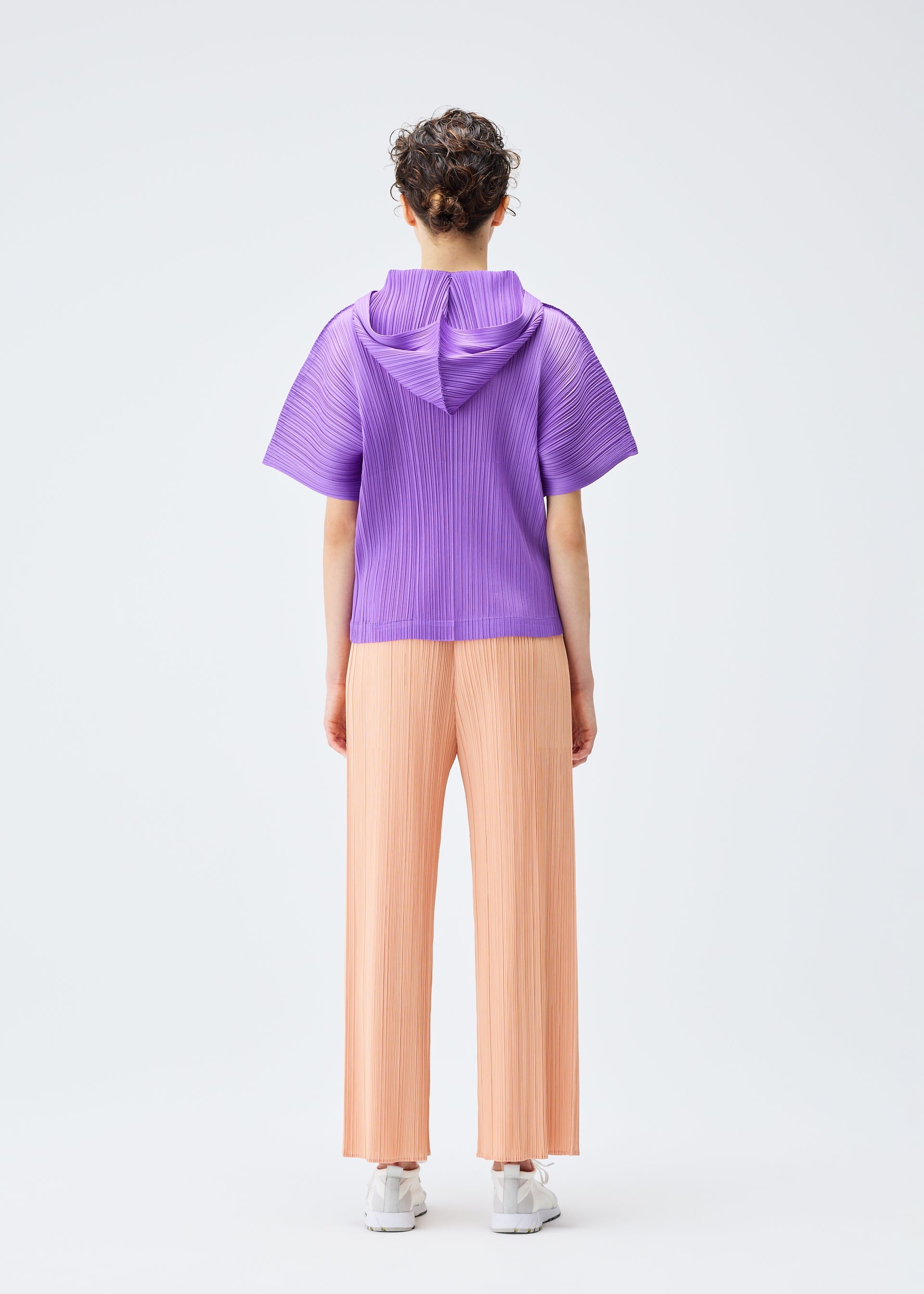 A model wears the PLEATS PLEASE ISSEY MIYAKE MONTHLY COLORS AUGUST trousers.